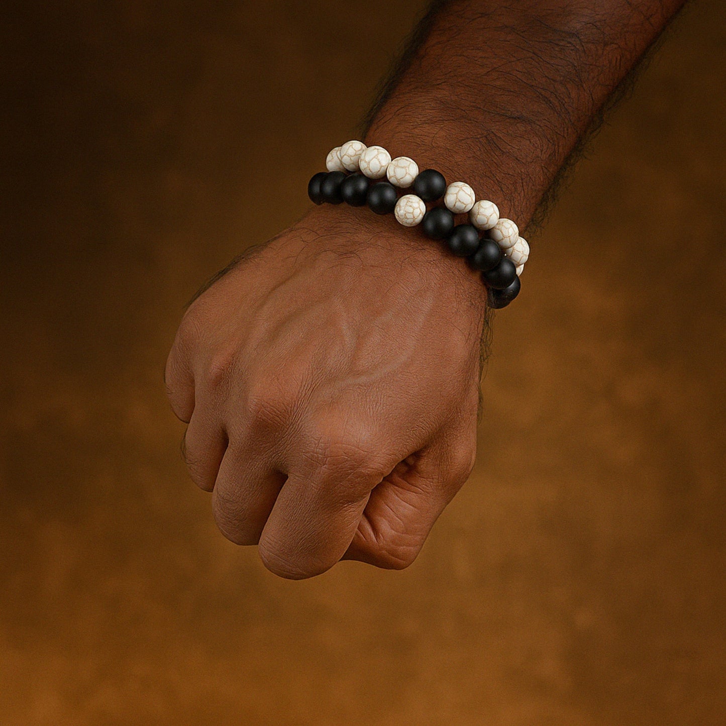 Hand wearing a black and white beaded bracelet on a brown background CrackleStoneBracelet