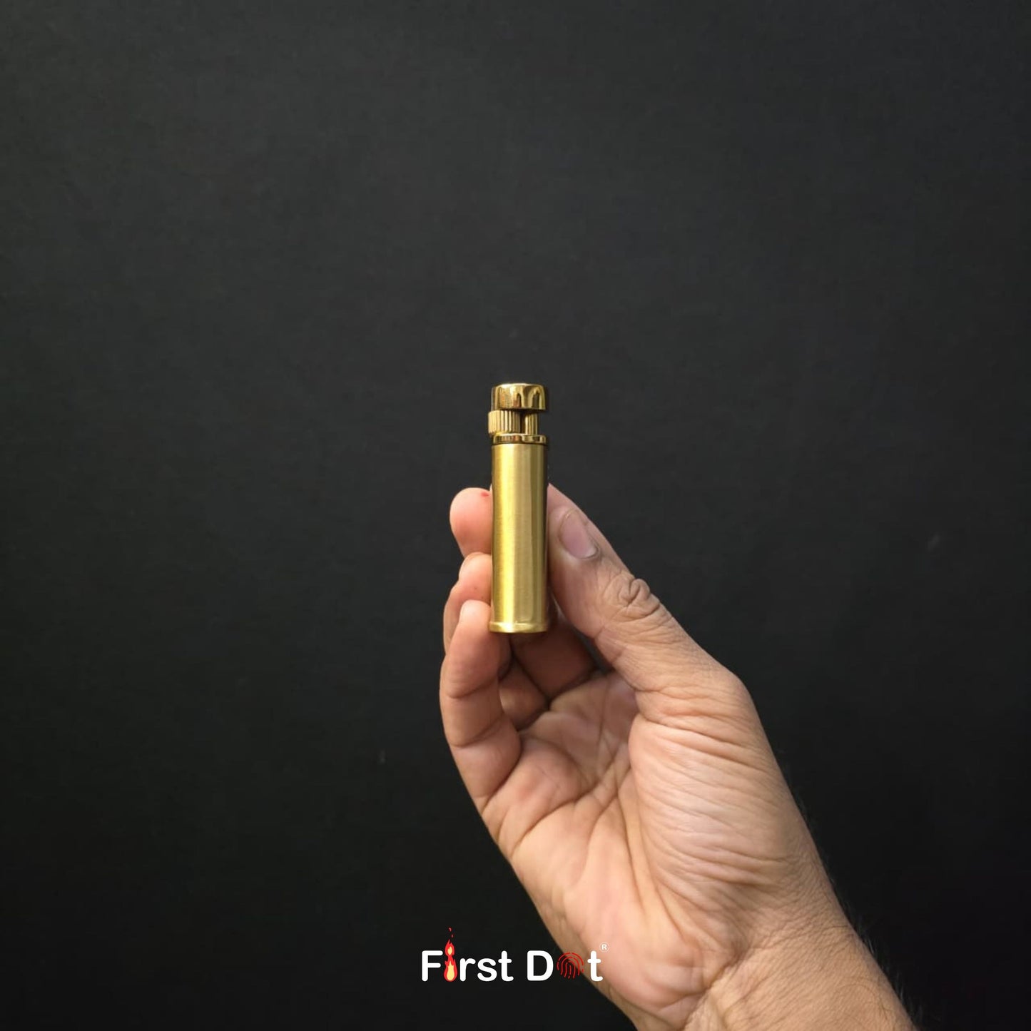 Hand holding a gold cylindrical object against a black background with 'First Dot' branding.