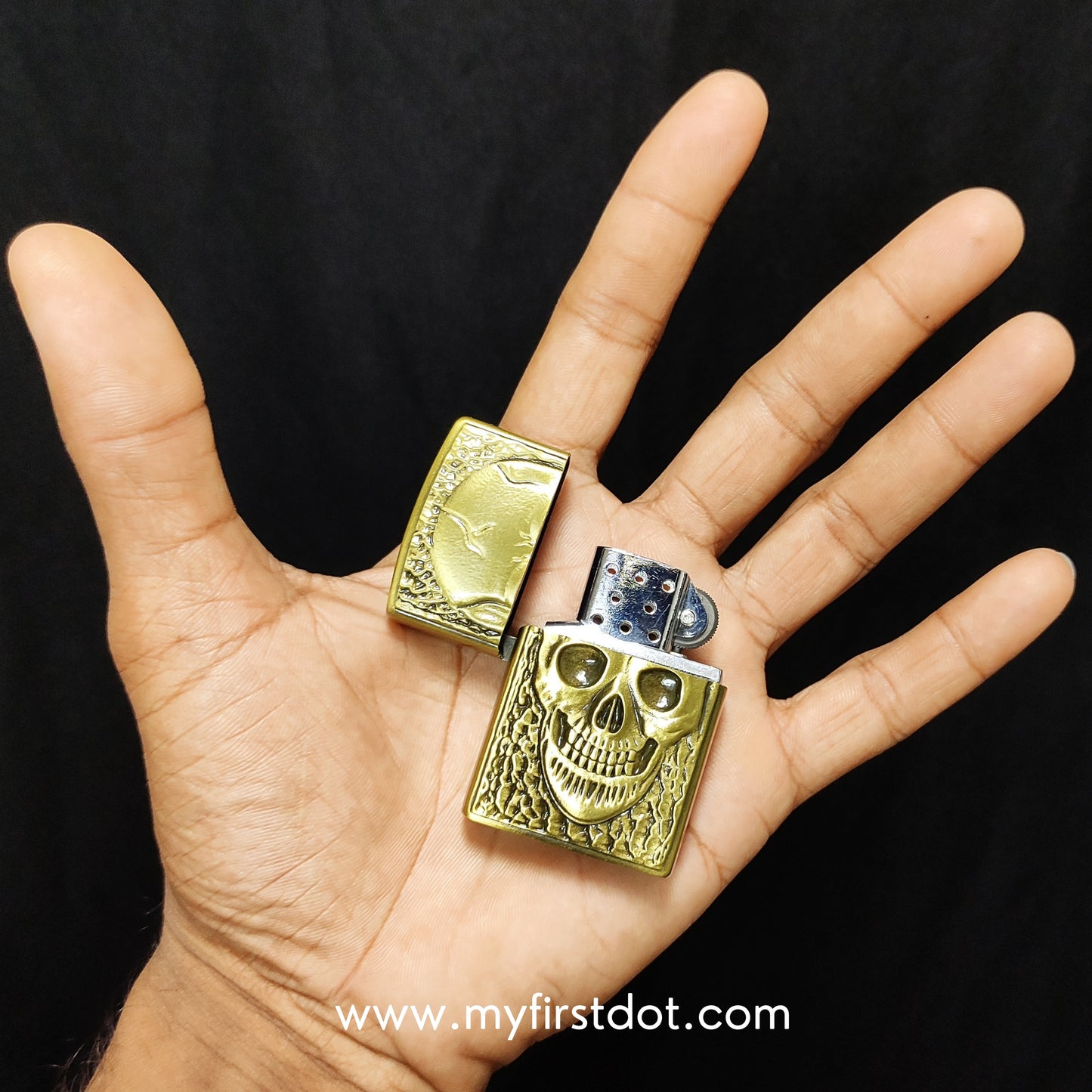 Gold skull design lighter held in a hand against a black background