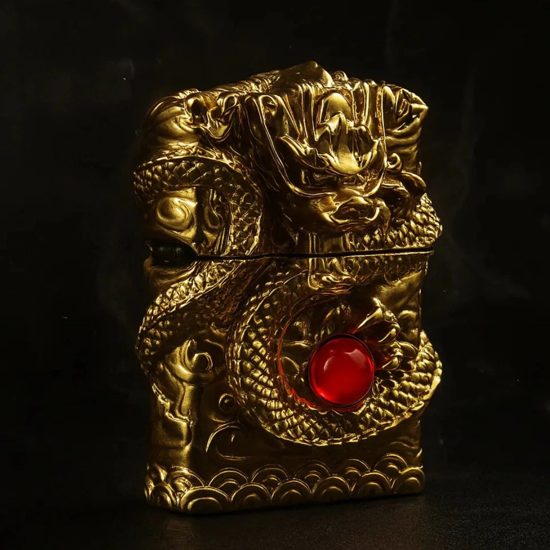 A gold dragon-engraved lighter with an intricate design and a red gemstone centerpiece is displayed against a matte black textured background with soft spotlighting, creating dramatic shadows and a luxury aesthetic.