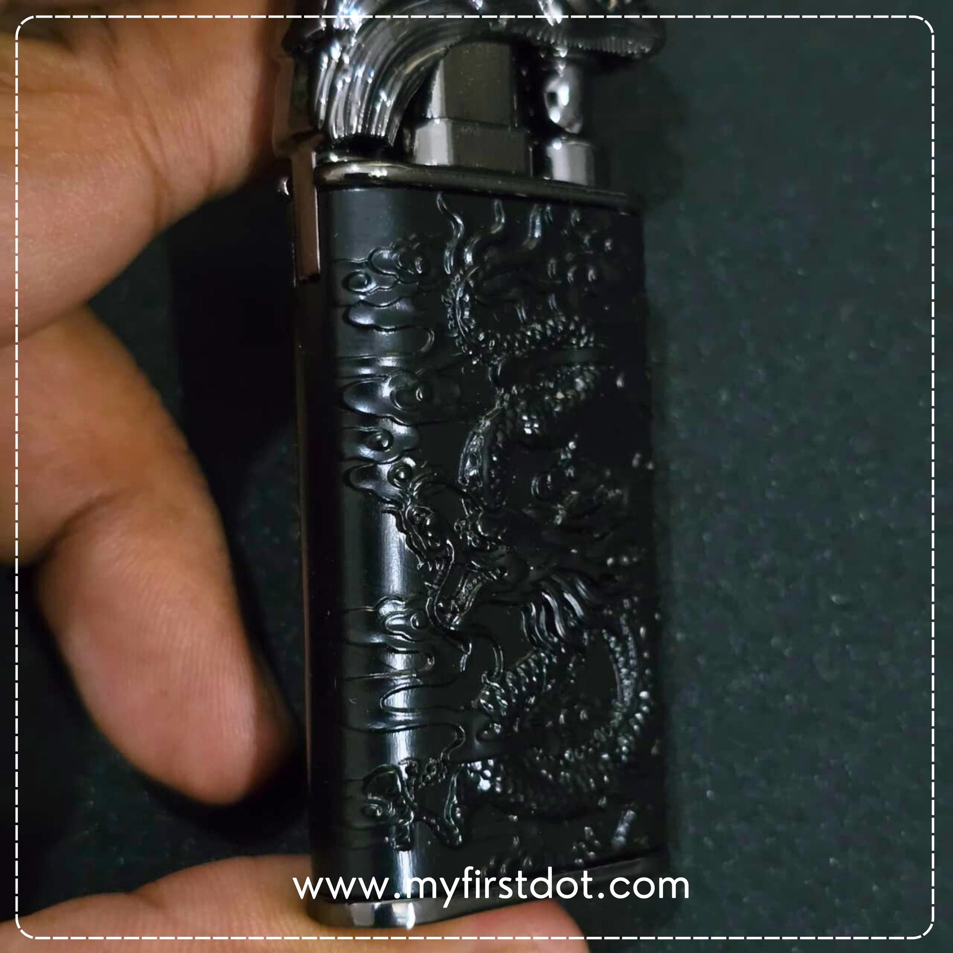 Black lighter with dragon design held by a hand against a dark background