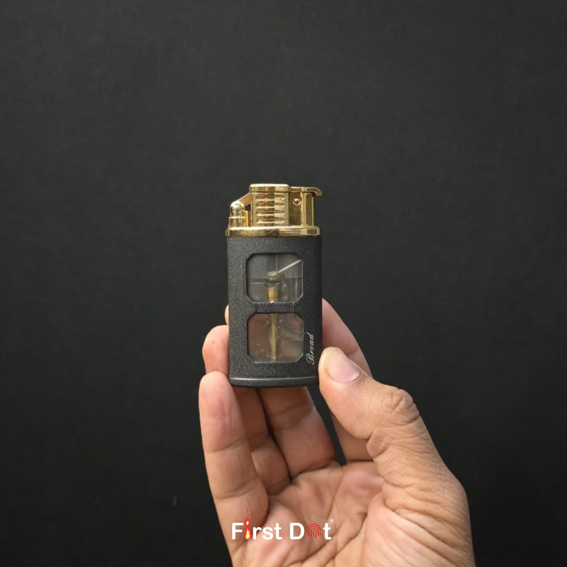 Hand holding a small black and gold device against a dark background with 'First Dot' branding.