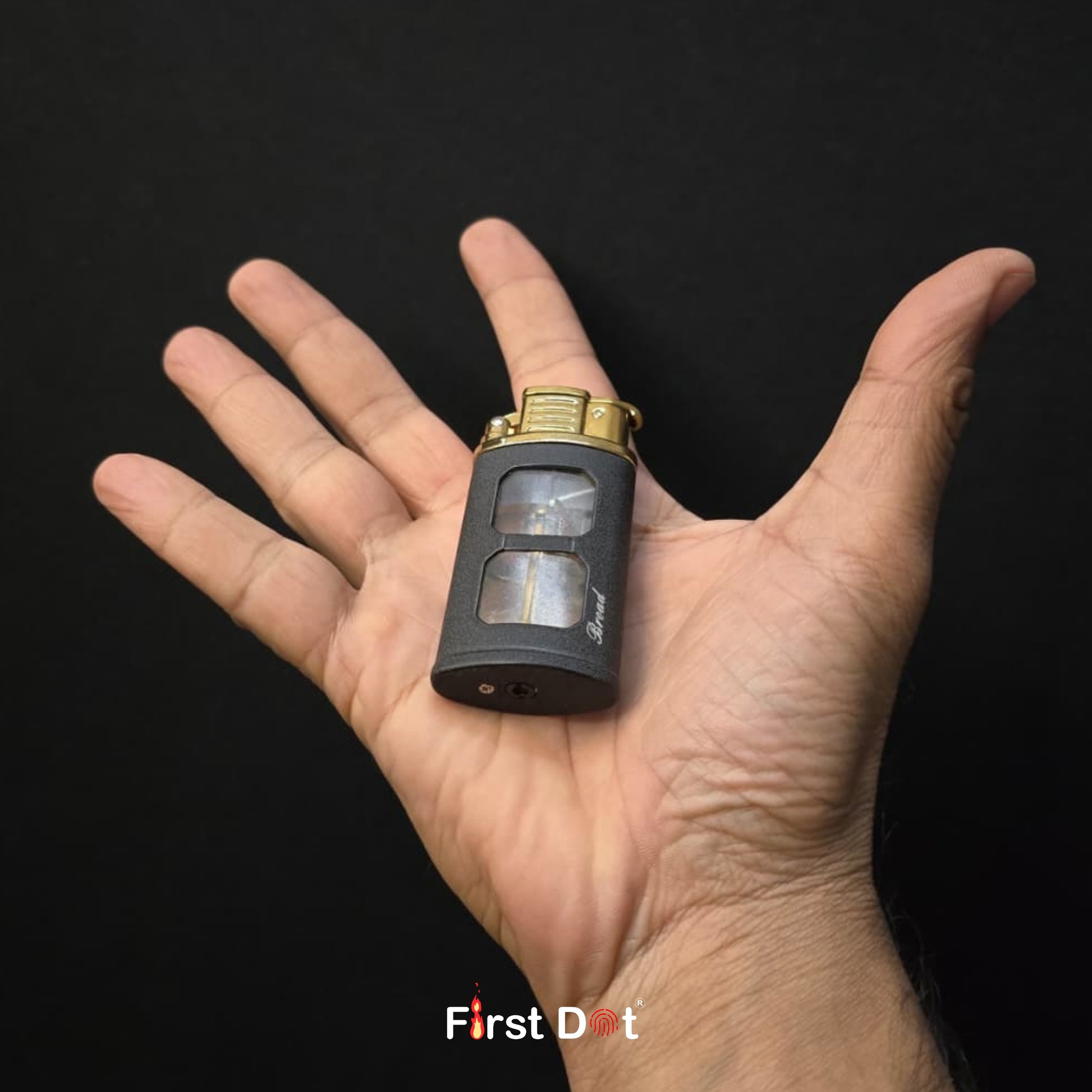 Hand holding a small black and gold device with 'First Dot' branding on a dark background
