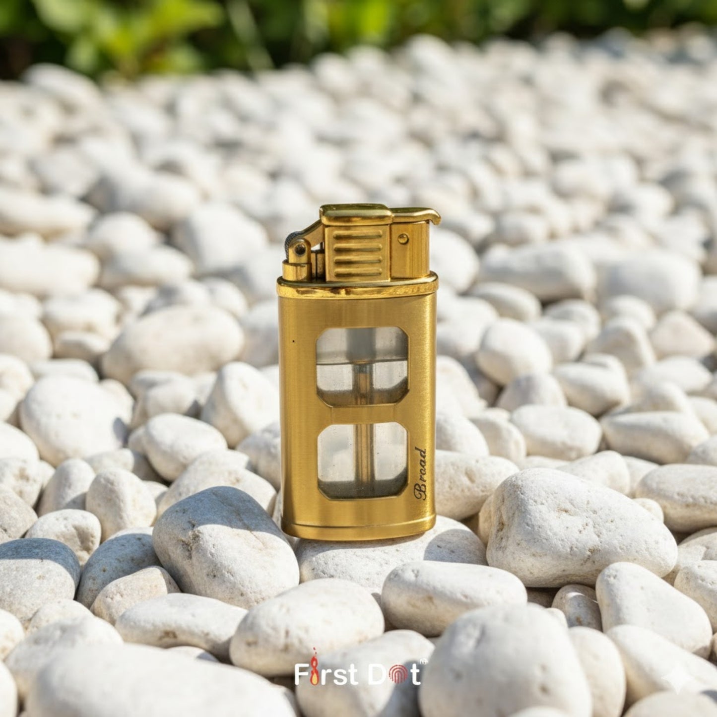 Gold lighter on pebbles with 'First Dot' branding