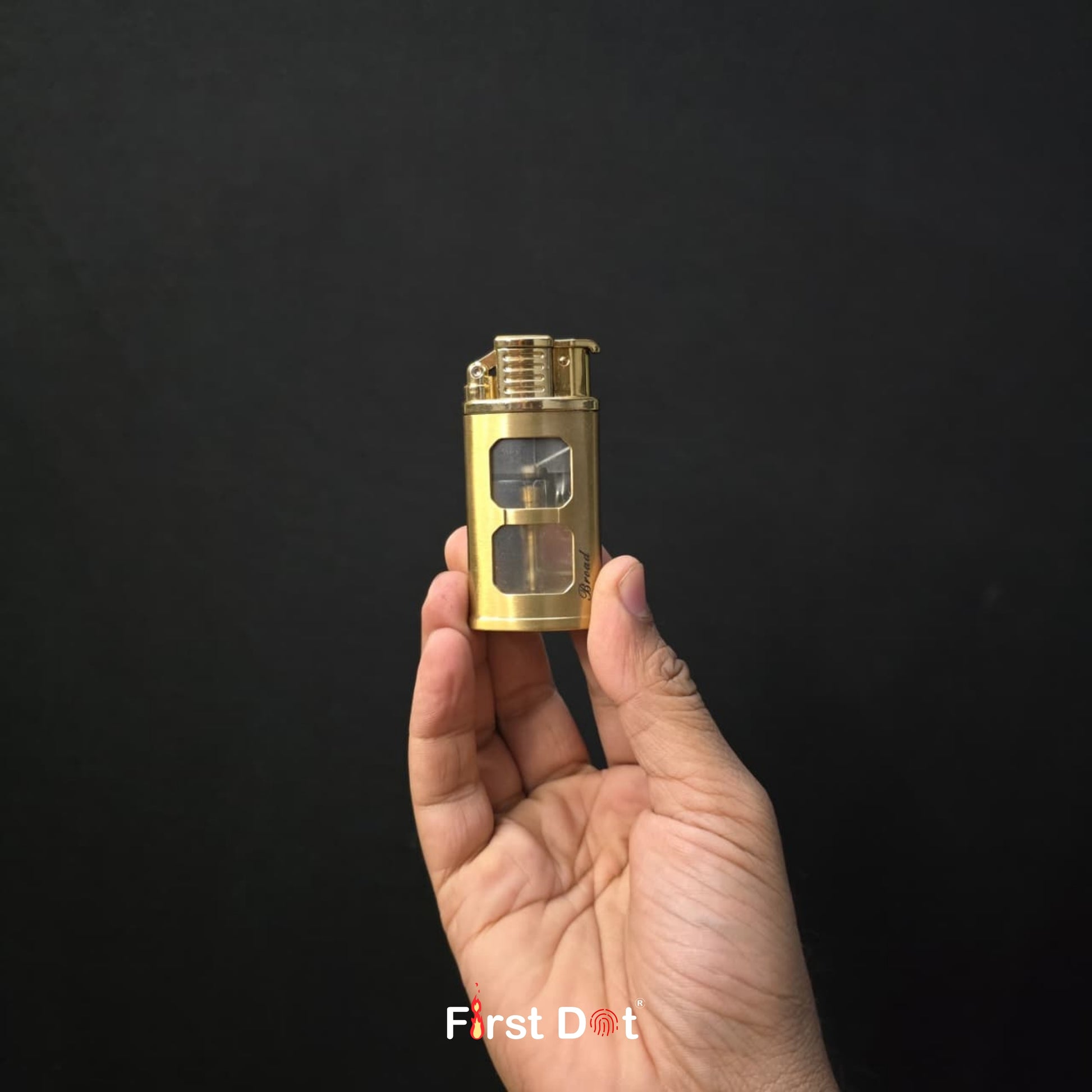 Hand holding a gold lighter against a black background with 'First Dot' branding.