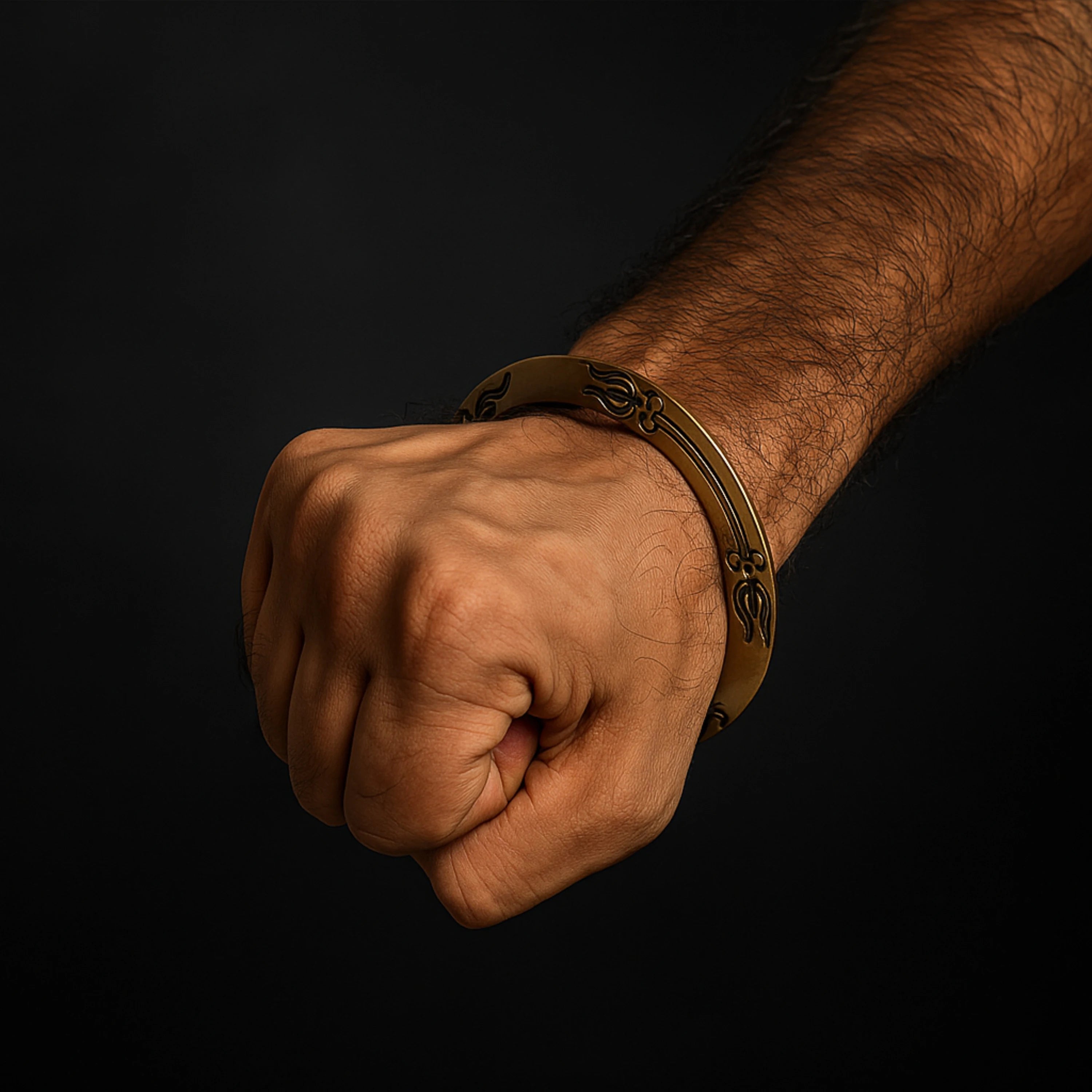Hand wearing a gold bracelet on a black background महाकाल Brass Kada