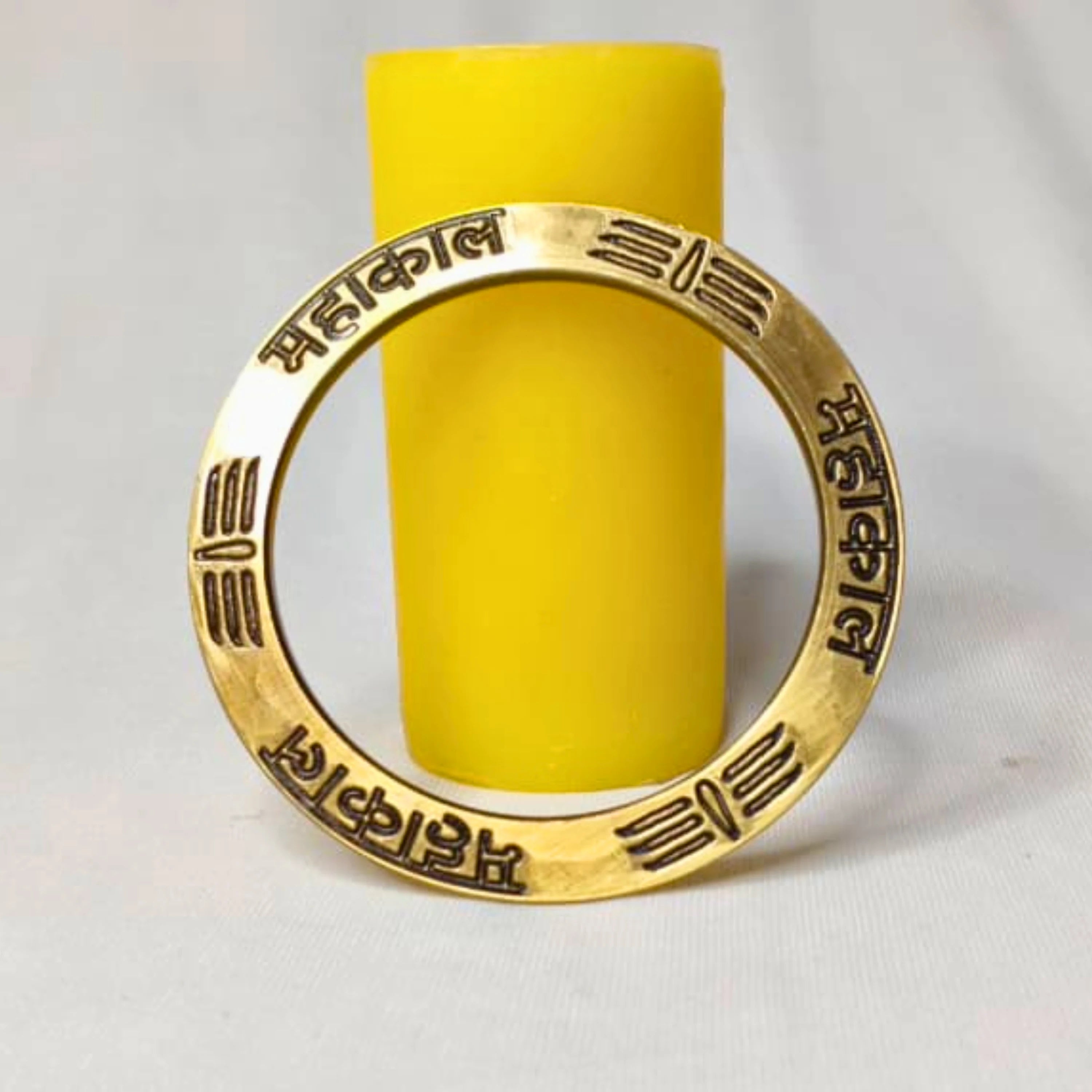 Gold ring with engraved text on a yellow cylindrical object against a gray background महाकाल Brass Kada