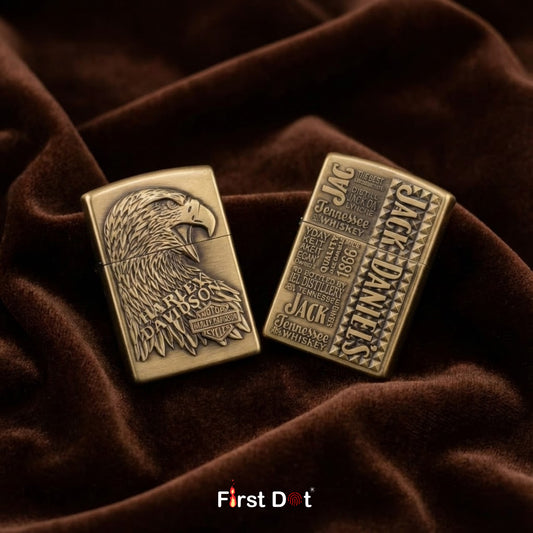 Two bronze-colored Jack Daniel's lighters on a brown fabric background with 'First Dot' branding.