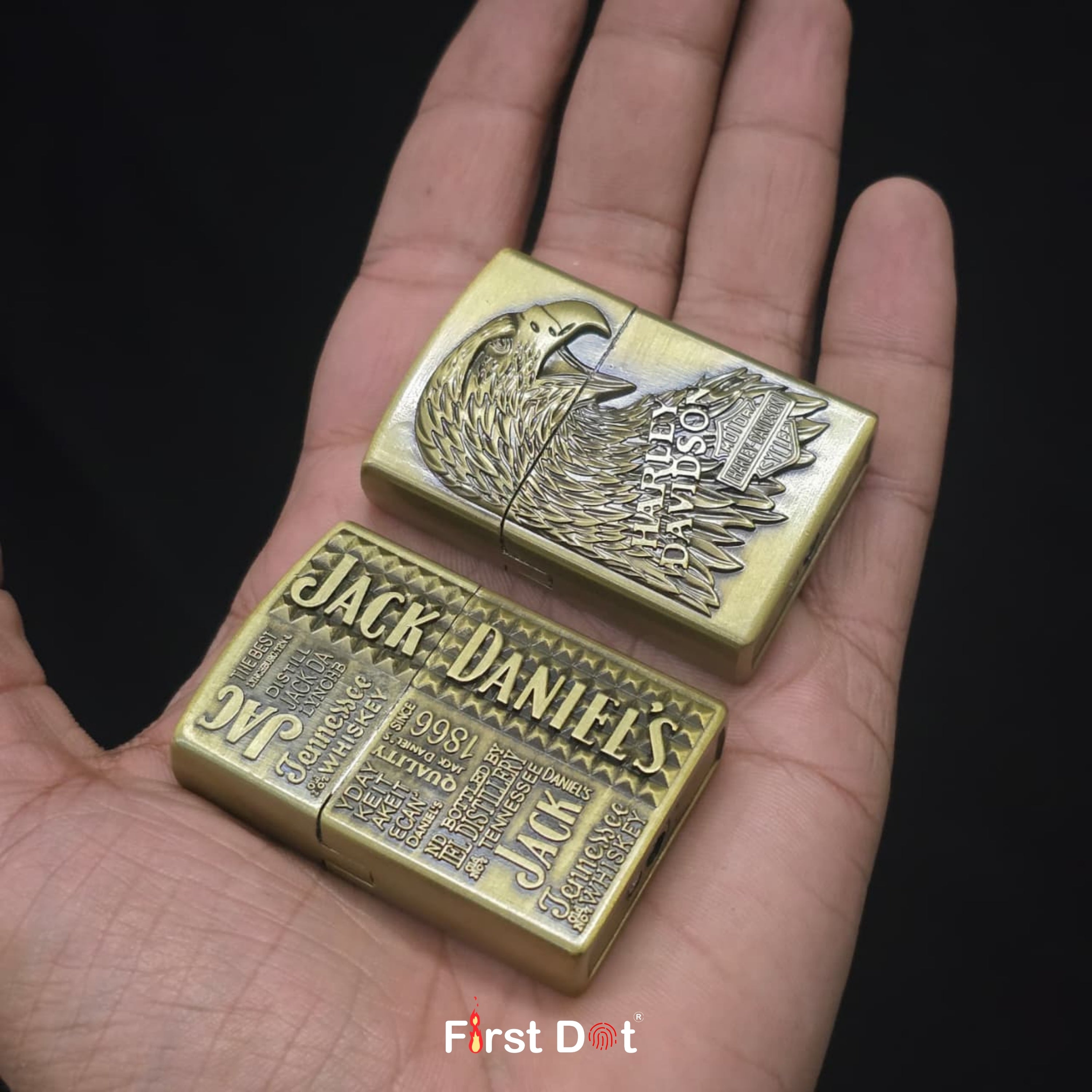 Two brass lighters with 'Harley Davidson' and 'Jack Daniel's' branding held in a hand against a dark background.