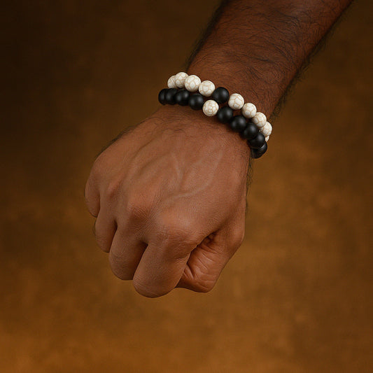 Hand wearing a black and white beaded bracelet on a brown background CrackleStoneBracelet