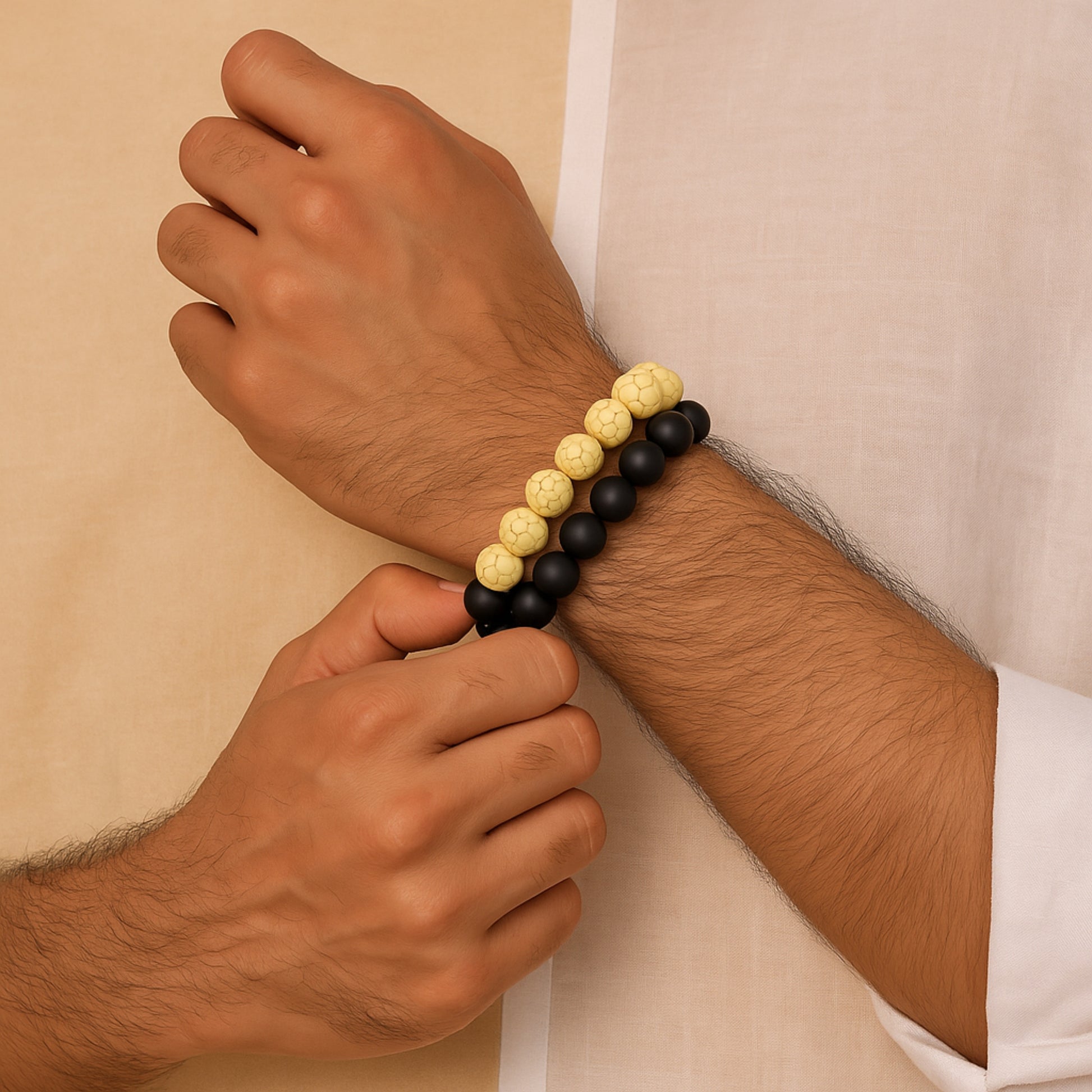 Hand wearing a black and yellow beaded bracelet against a beige  CrackleStoneBraceletbackground