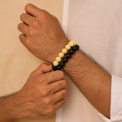 Hand wearing a black and yellow beaded bracelet against a beige  CrackleStoneBraceletbackground
