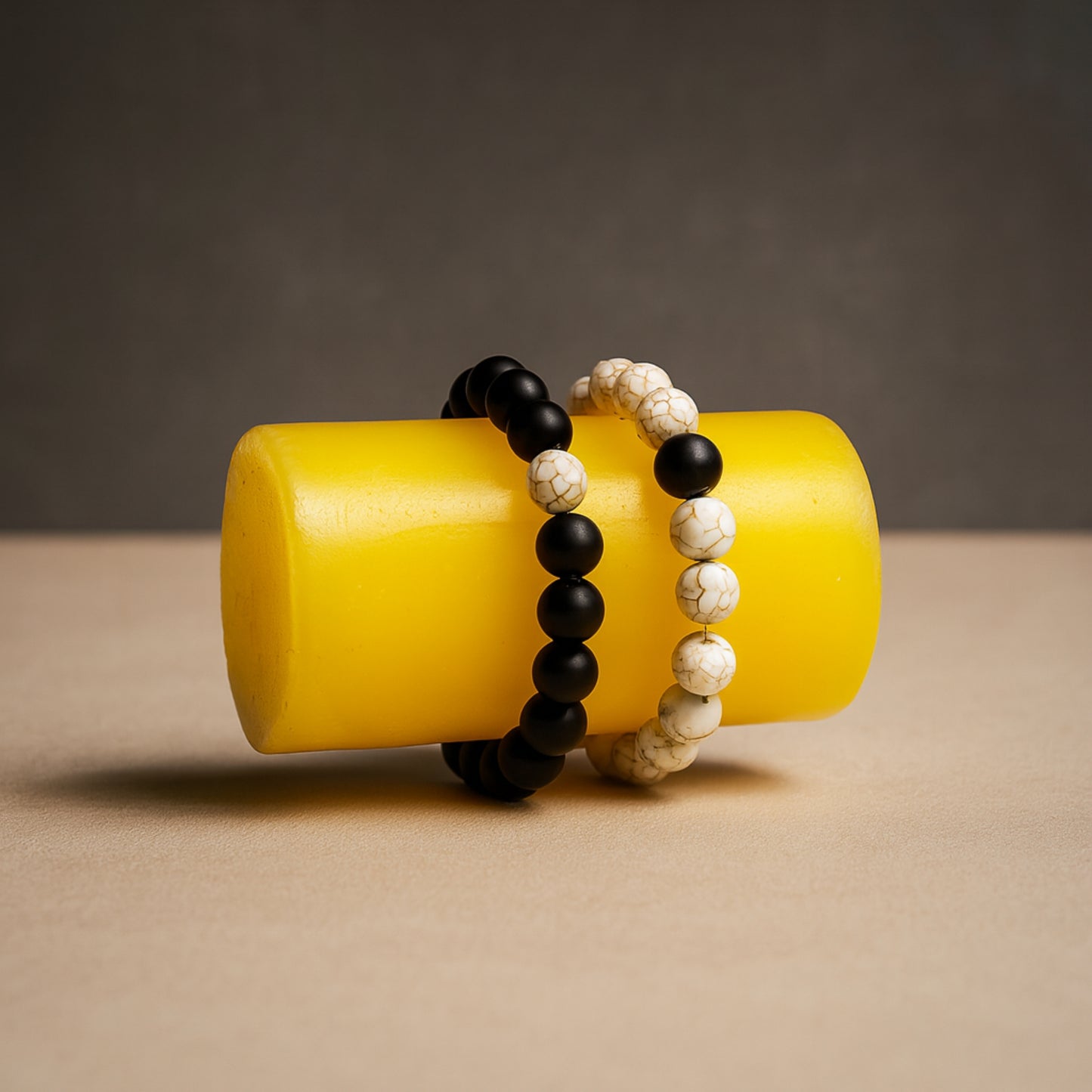 Two beaded bracelets on a yellow cylindrical object with a neutral background CrackleStoneBracelet
