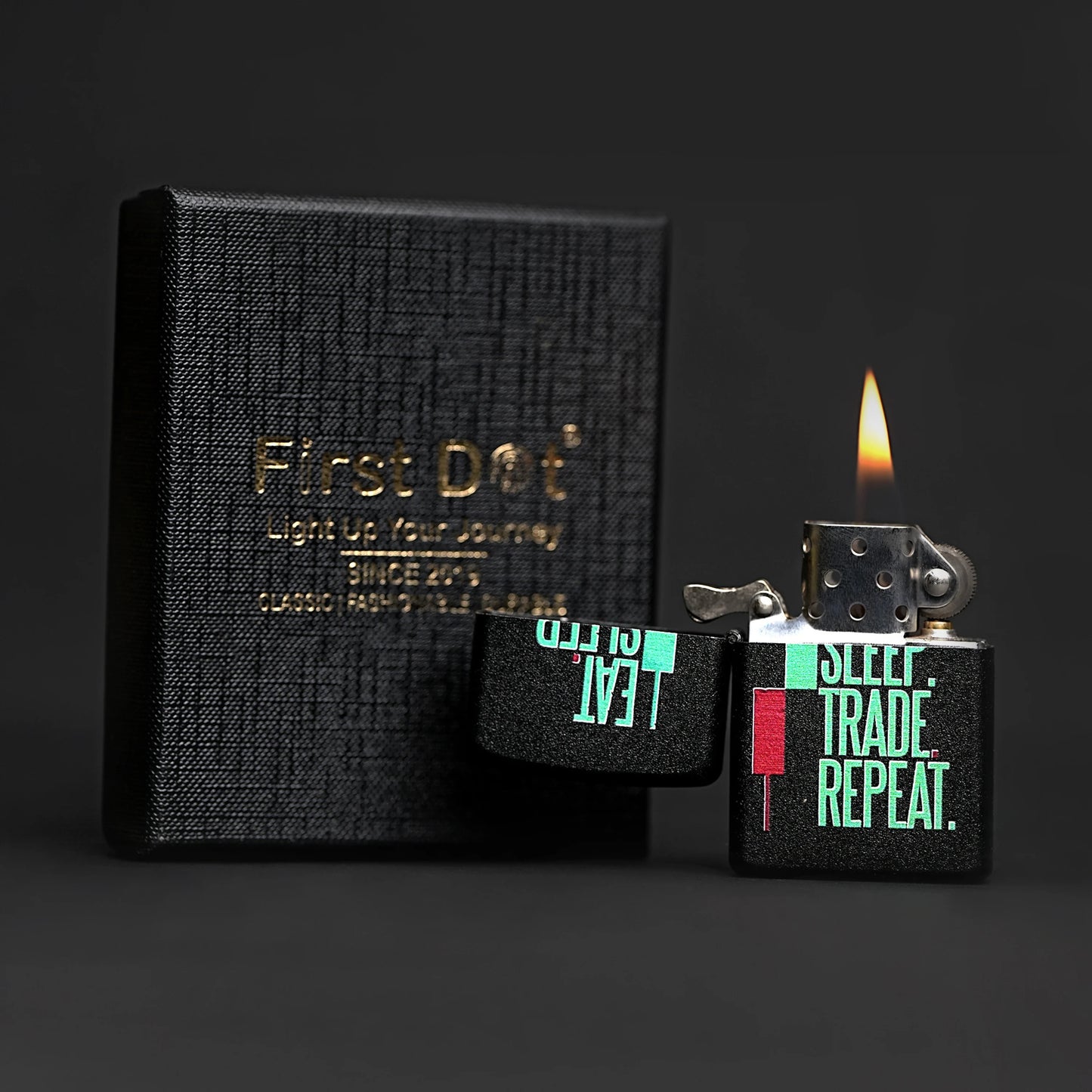 Black textured notebook with 'First Dog' branding and a lit lighter with text on a dark background Eat Sleep Trade Repeat Candle Premium Refillable Cigarette Lighter