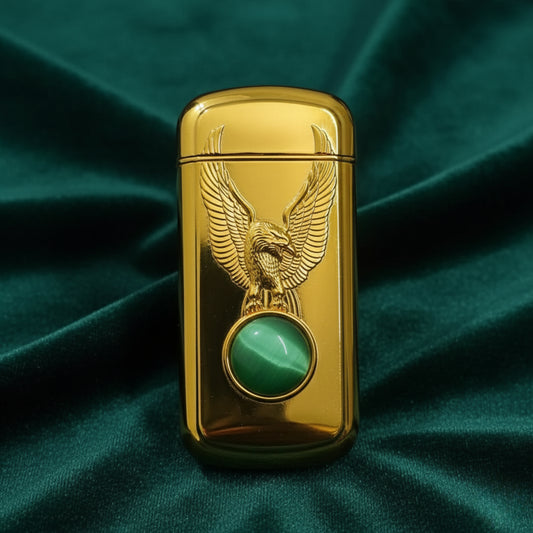 Gold lighter with eagle design and green gemstone on a green fabric background