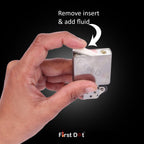 Hand holding a small lighter with 'First Dot' branding, showing how to remove an insert and add fluid.