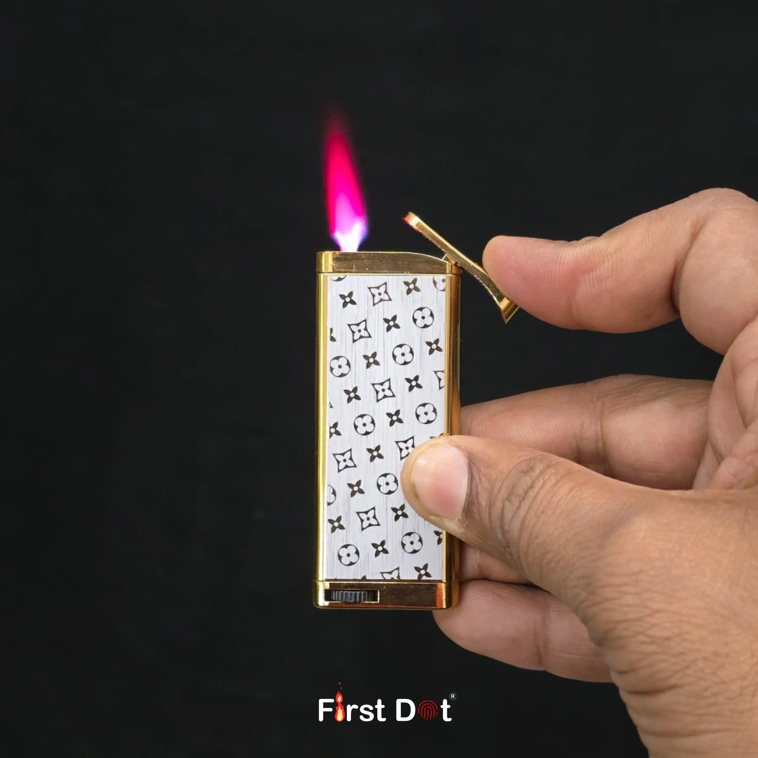 Hand holding a gold lighter with a white design, lit against a dark background.