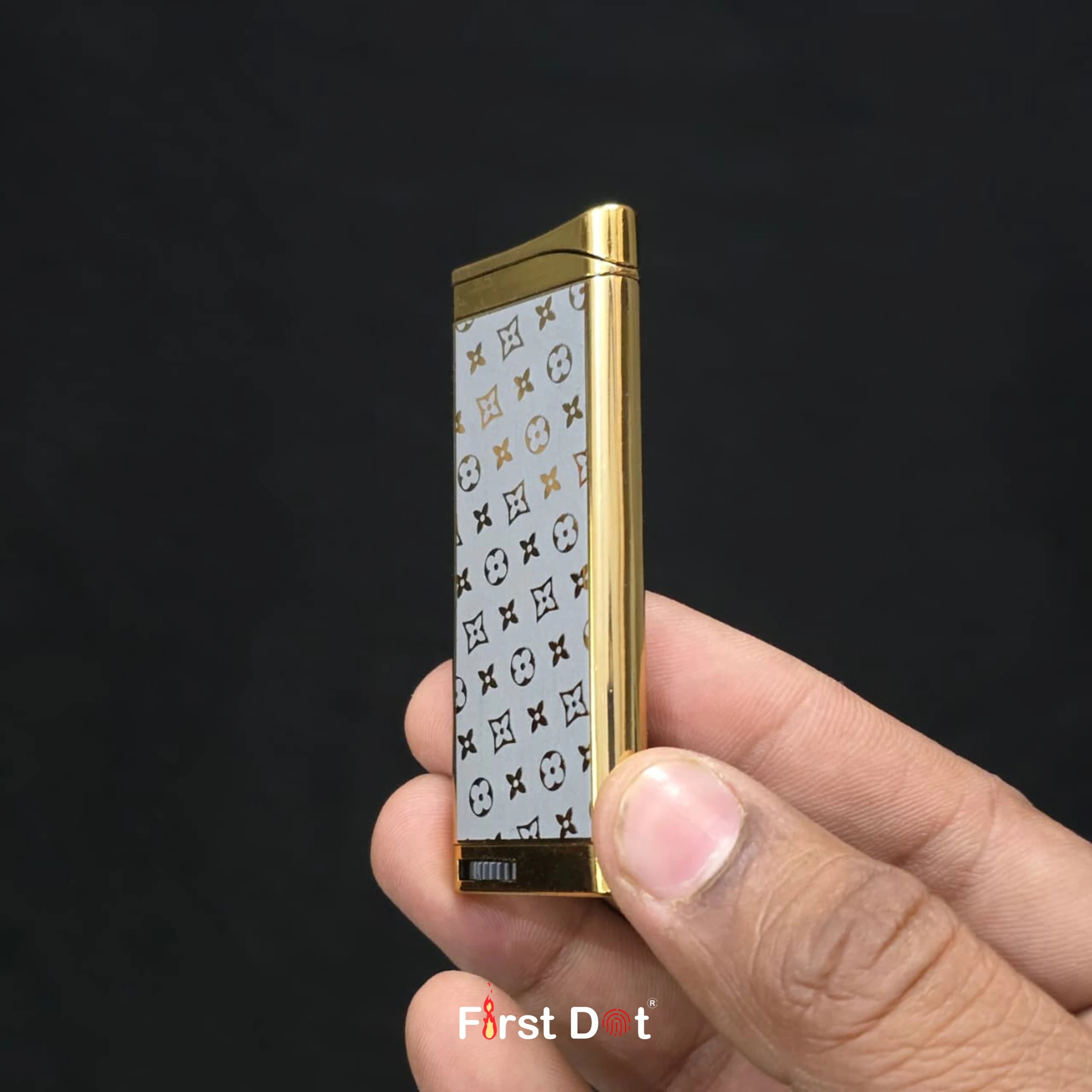 Gold lighter with patterned cover held in a hand against a black background
