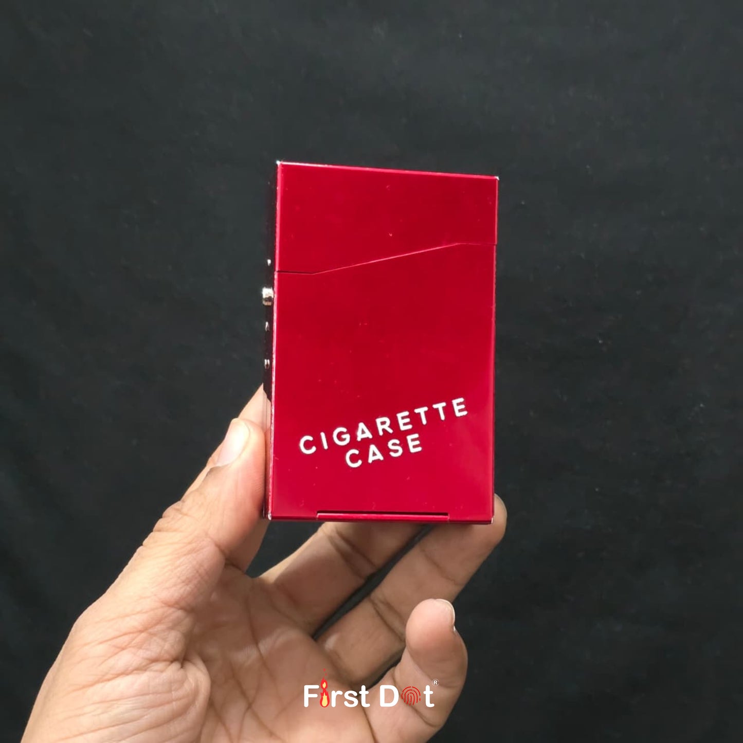Red cigarette case held in a hand against a black background