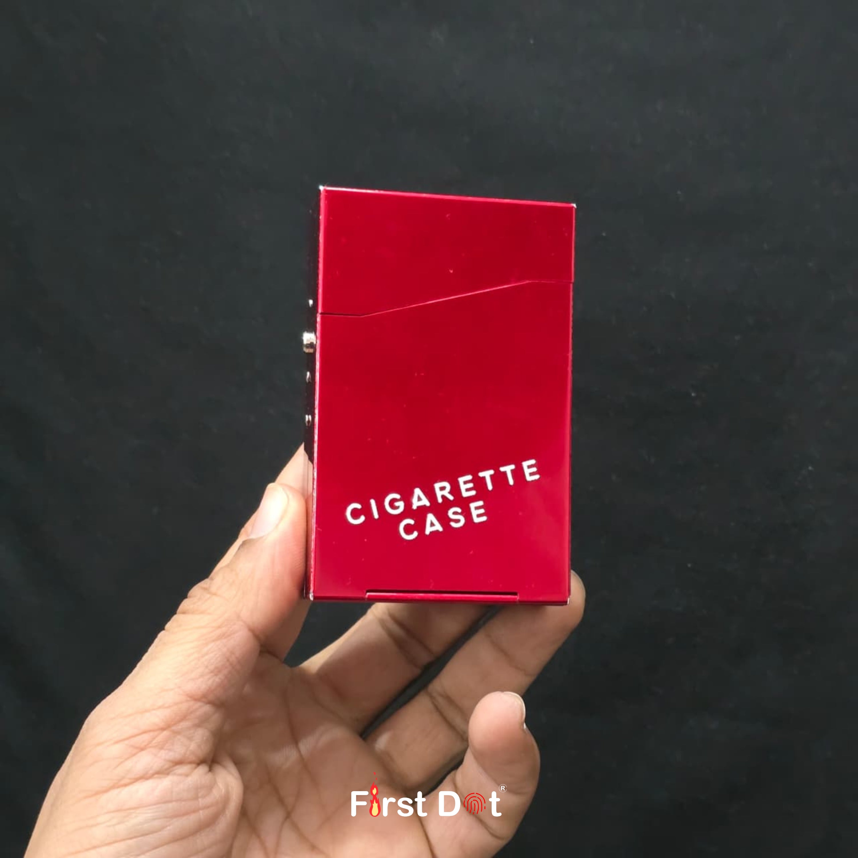 Red cigarette case held in a hand against a black background