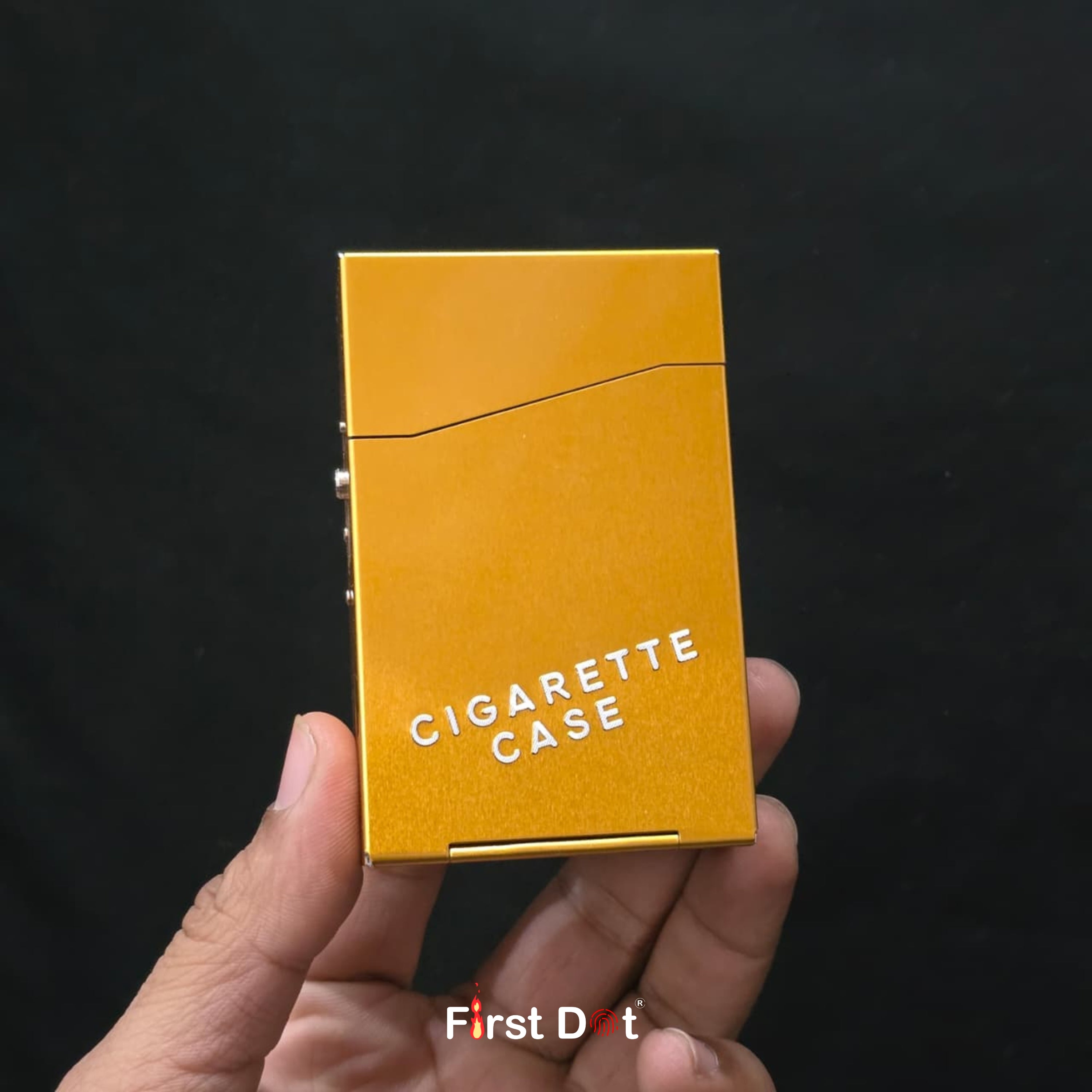 Gold cigarette case held in a hand with a black background