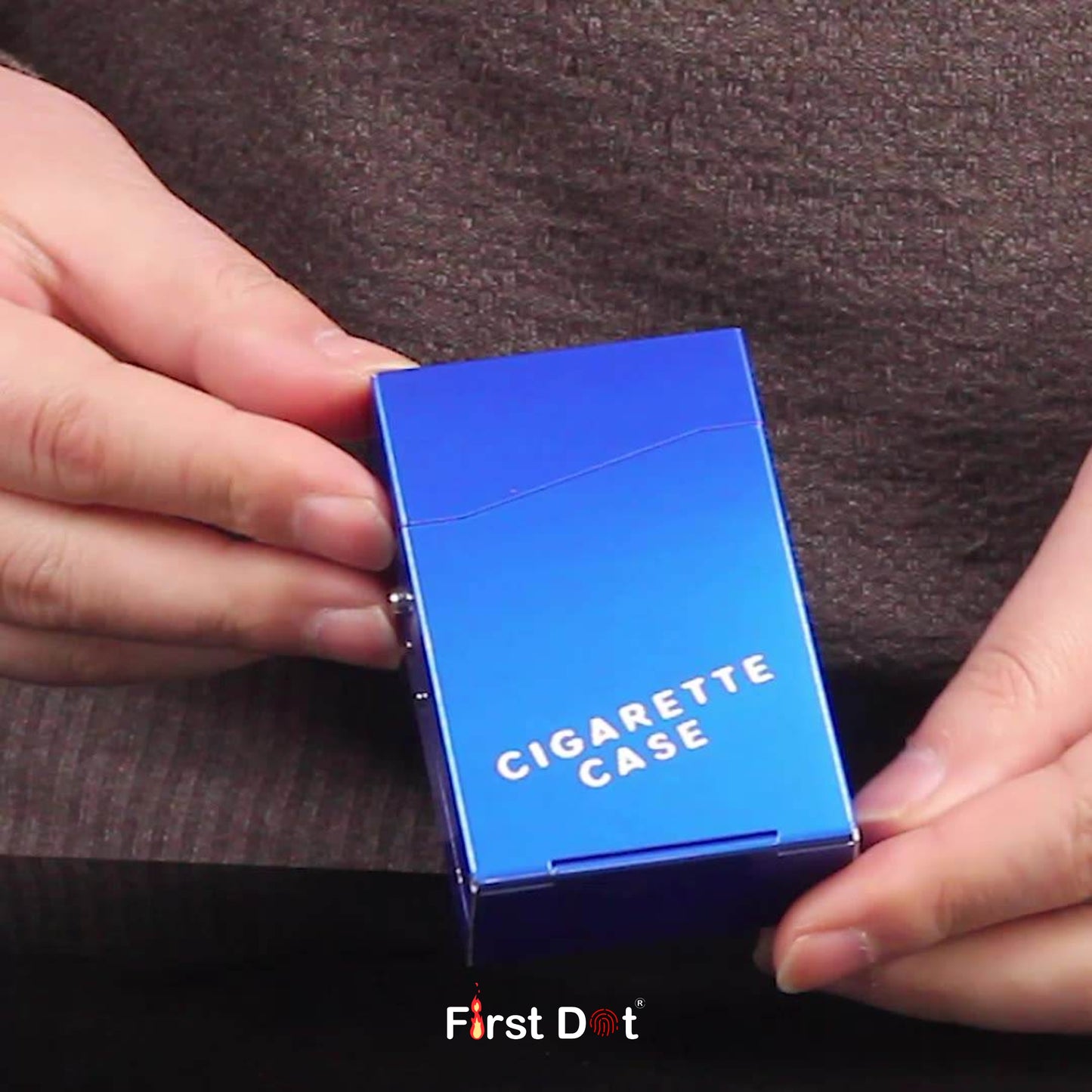 Blue cigarette case held by hands with 'First Dot' branding.