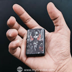 Hand holding a zippo lighter with a design on a black background