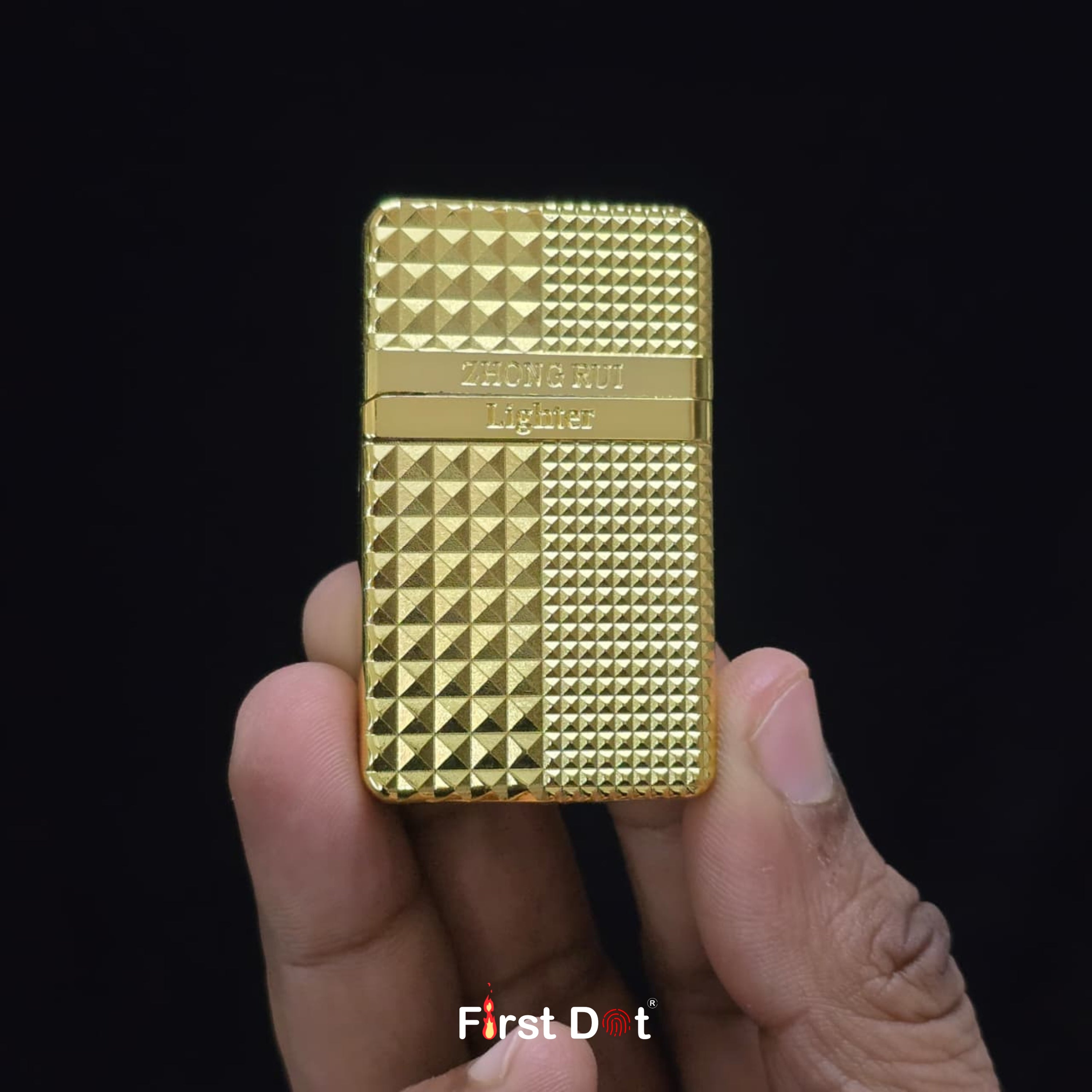 Gold lighter held in a hand against a black background