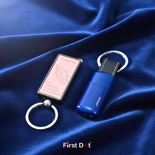 Two keychains on a blue fabric background with 'First Dot' branding.