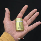 Gold cylindrical lighter with Eiffel Tower design held in a hand against a black background, featuring 'First Dot' branding.