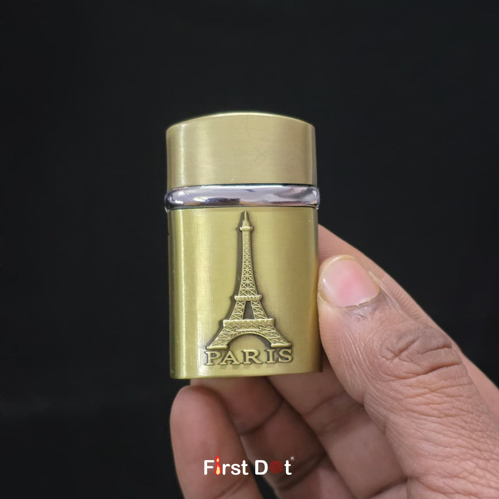 Gold lighter with Eiffel Tower design held by a hand against a black background