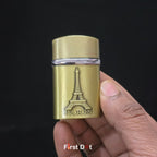 Gold lighter with Eiffel Tower design held by a hand against a black background