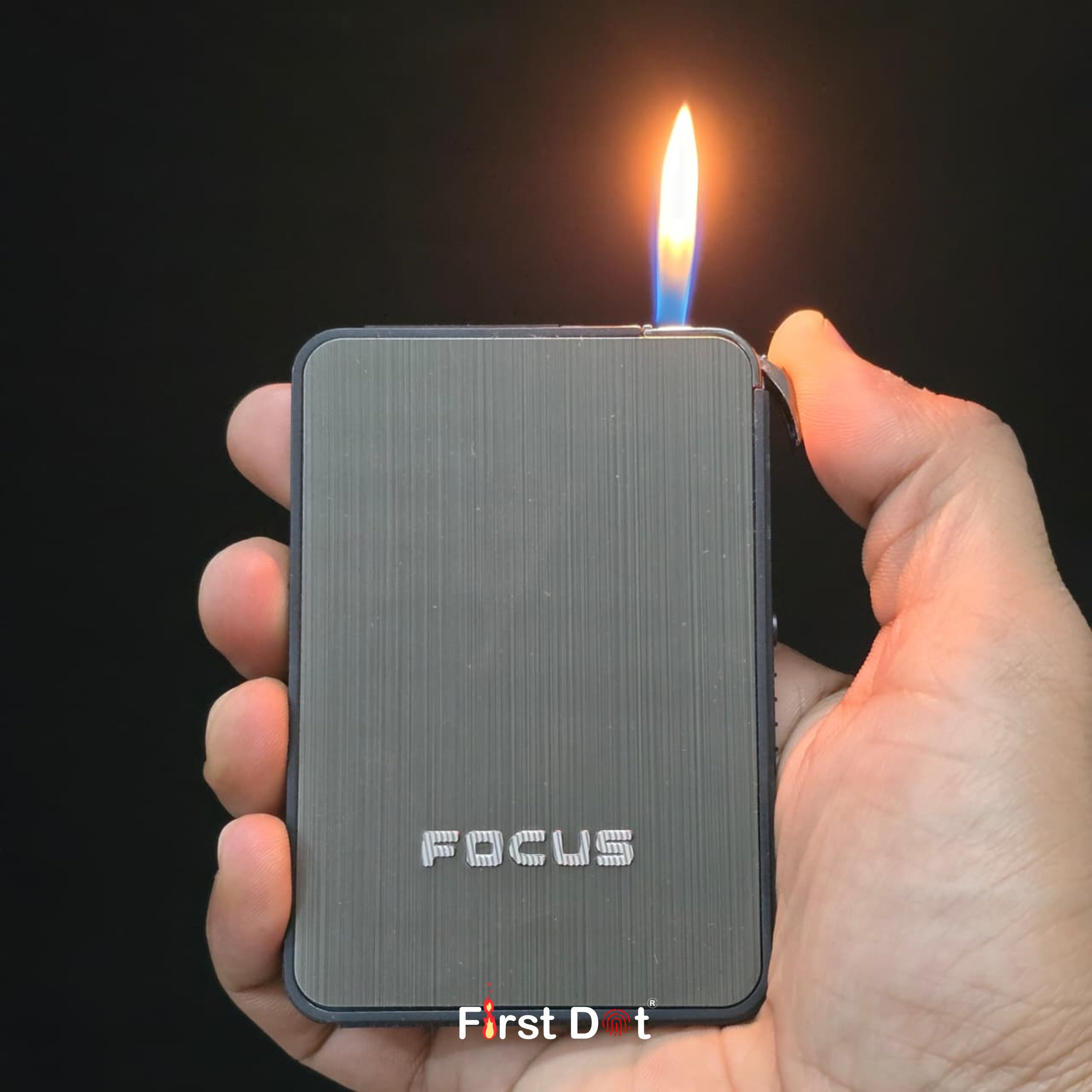 Hand holding a 'FOCUS' lighter with a flame against a dark background cigarette case with built-in lighter