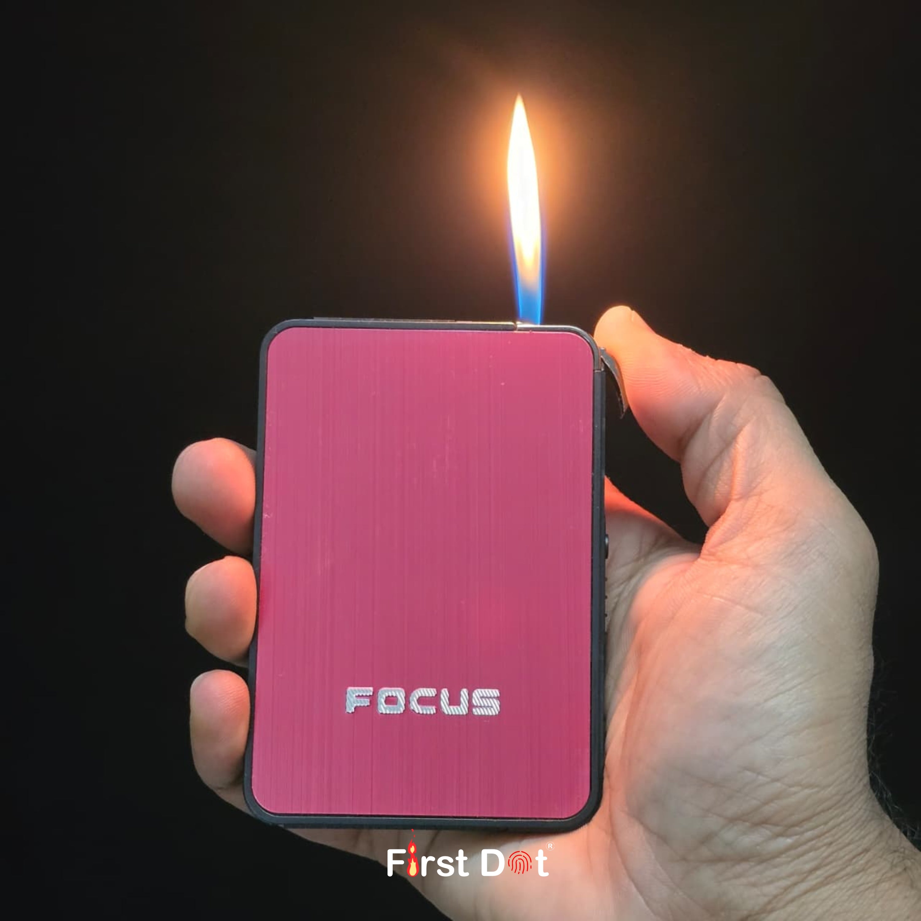 Hand holding a Red Cigarette Case with Lighterwith 'FOCUS' branding, lit by a blue flame against a dark background.