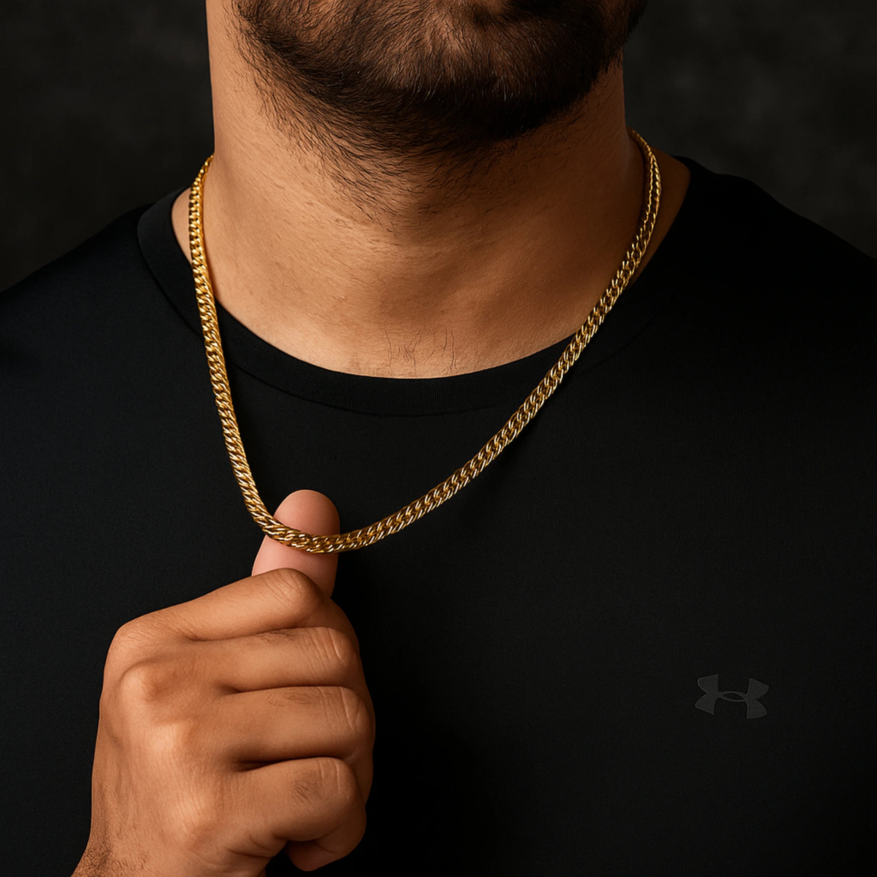 Gold chain necklace being held by a person wearing a black shirt with a brand logo. First Dot Italian Golden Curb Chain for Men
