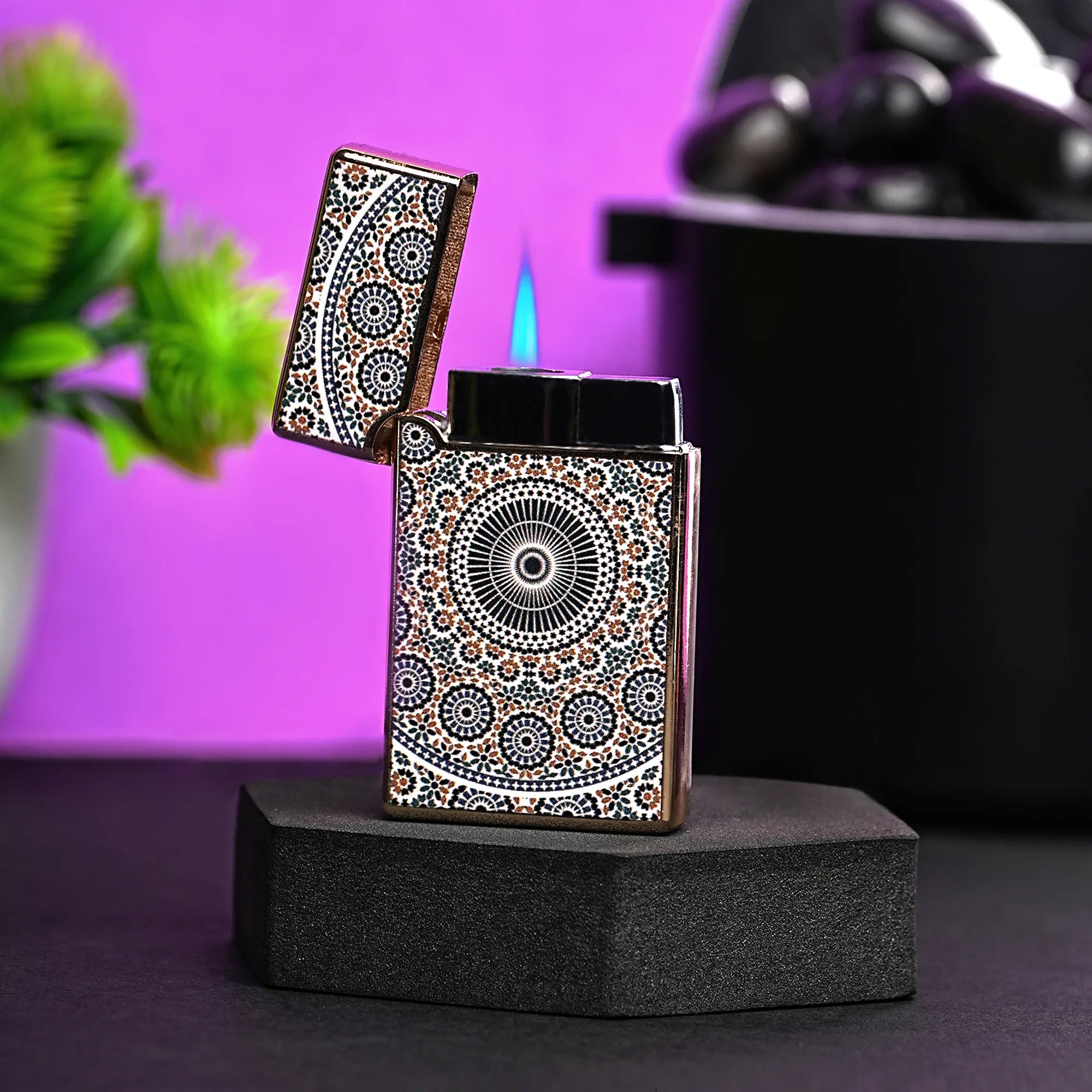 Decorative lighter with intricate patterns on a black stand against a purple background 