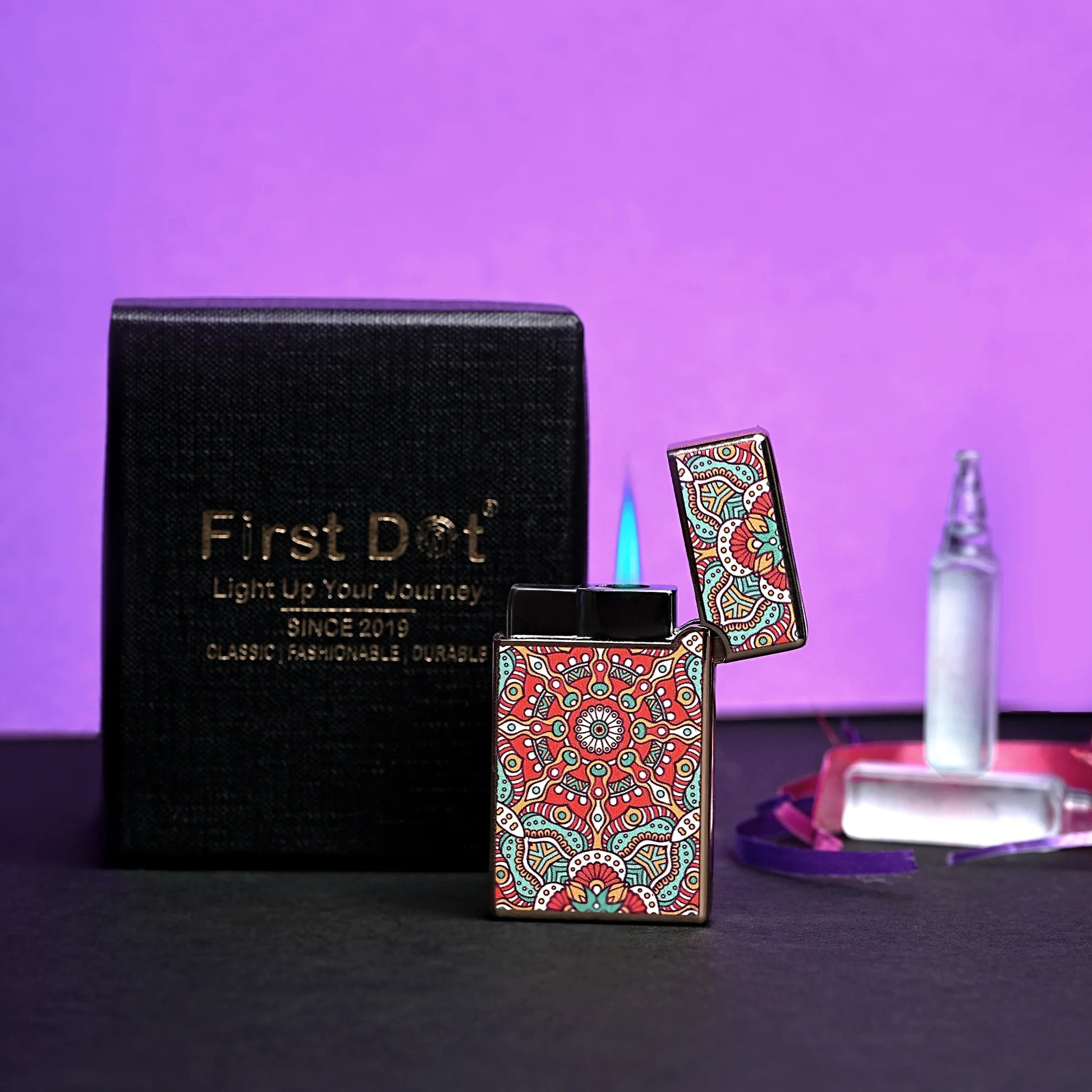Colorful lighter with intricate design on a black box labeled 'First Dot' against a purple background. Mandala Art Jet Flame Windproof Lighter