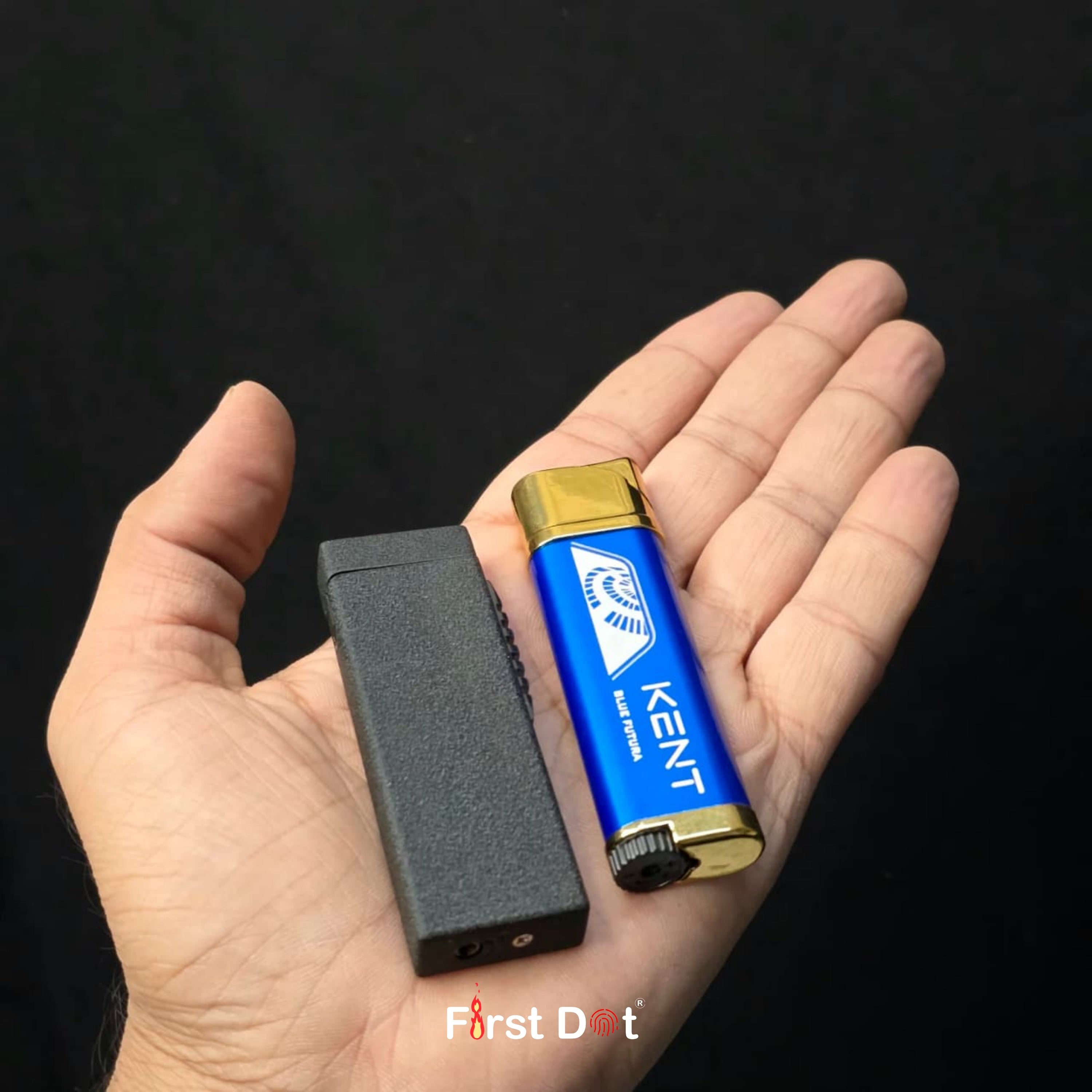 Hand holding a blue KENT lighter and black device against a black background