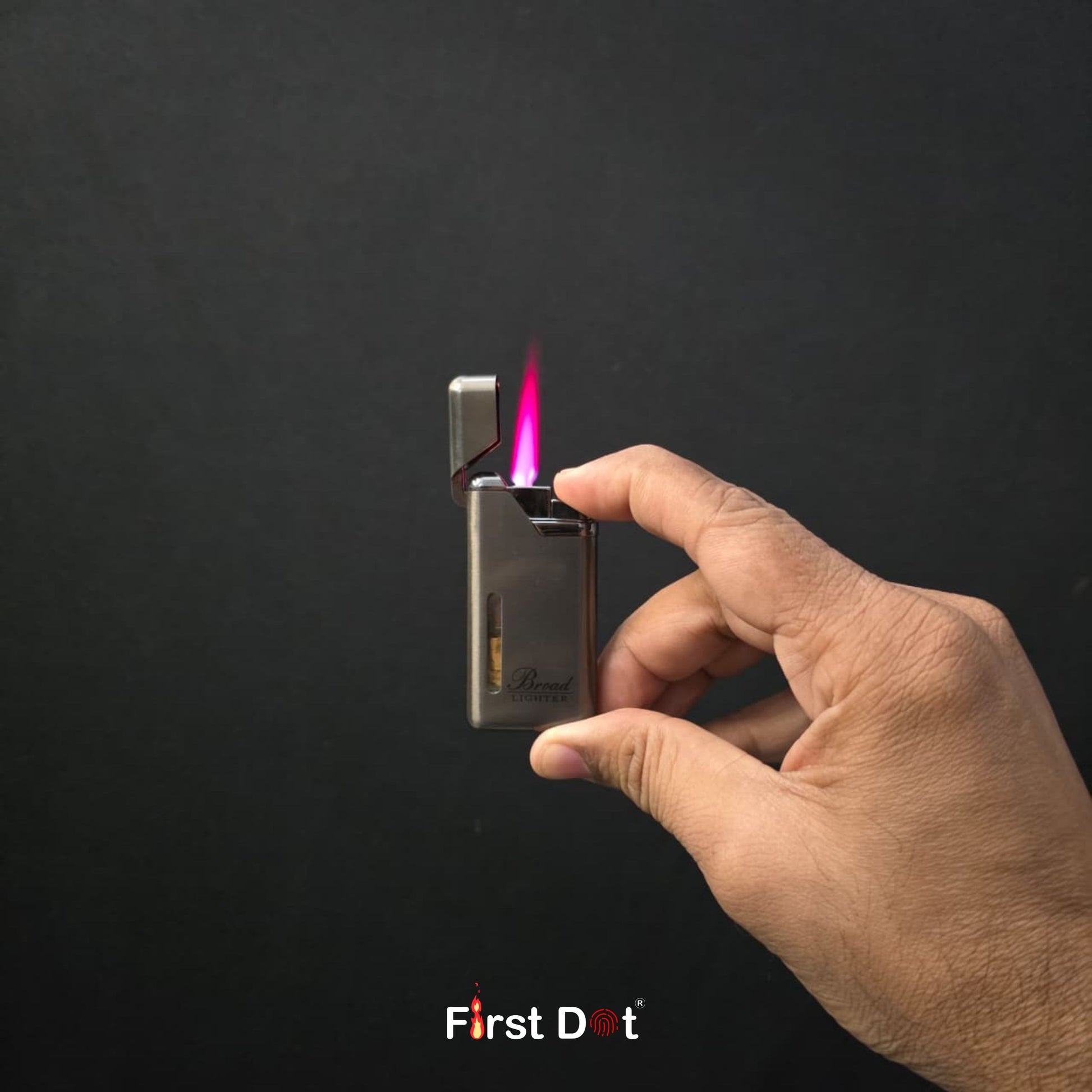 Hand holding a lighter with a visible flame against a dark background, featuring the 'First Dot' brand.