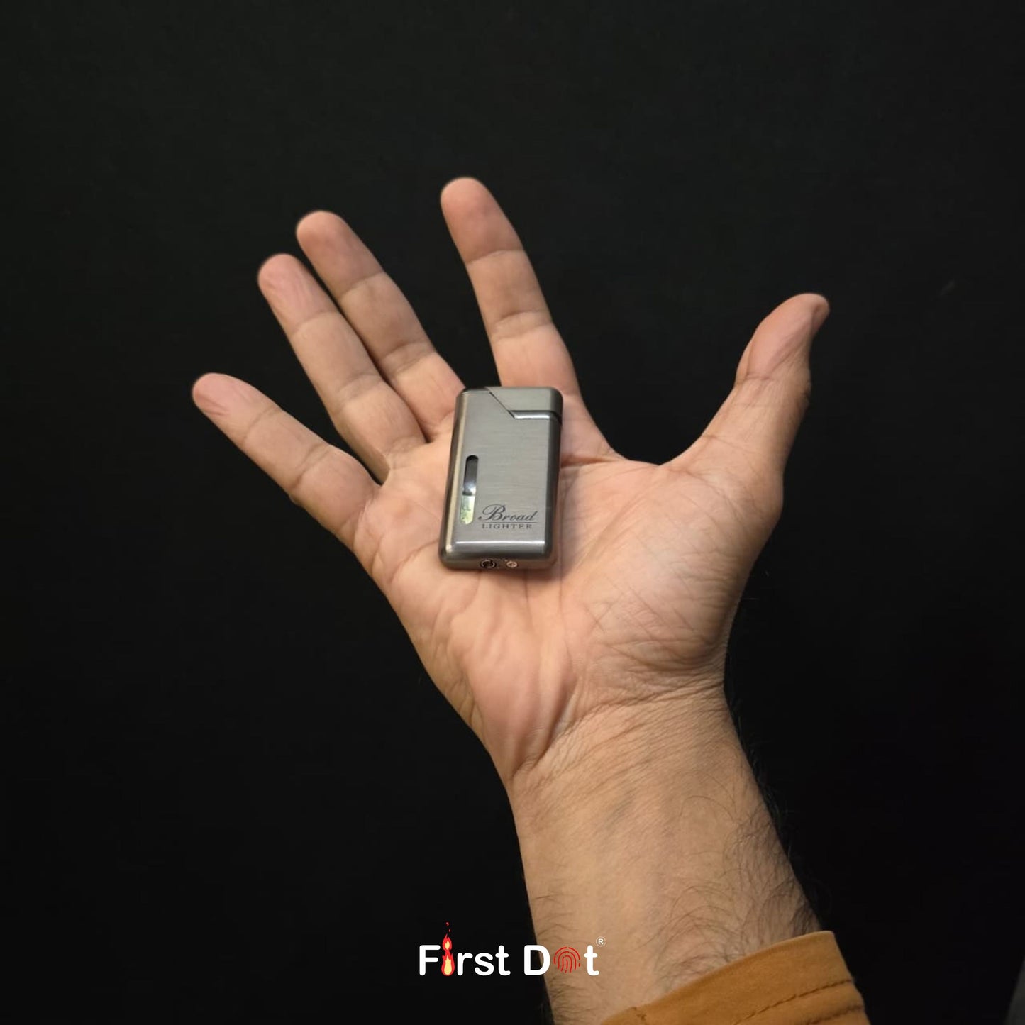 Hand holding a small electronic device labeled 'First Dot' against a black background