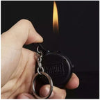 Hand holding a black keychain lighter with flame in the background
