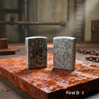 Two metallic lighters with intricate designs on a rusted surface, with 'First Dot' branding.
