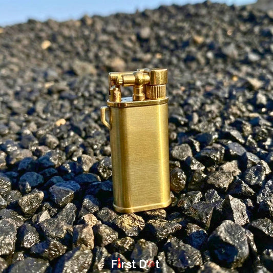 Gold lighter on a bed of rocks with 'First Dot' branding.