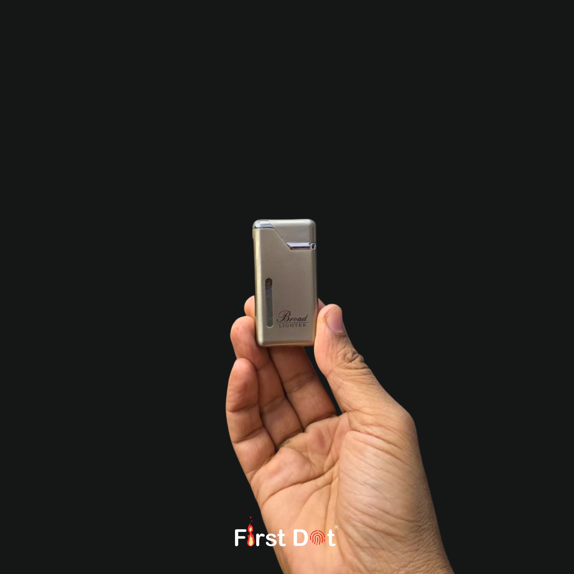 Hand holding a small silver lighter against a black background with 'First Dot' branding.
