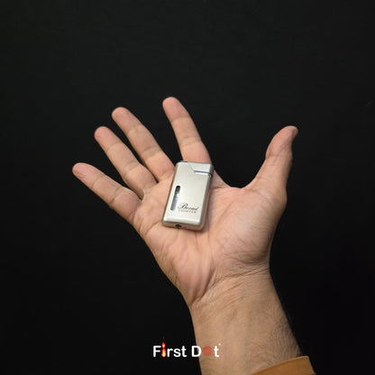 Hand holding a small silver lighter with 'Briquet' branding against a black background