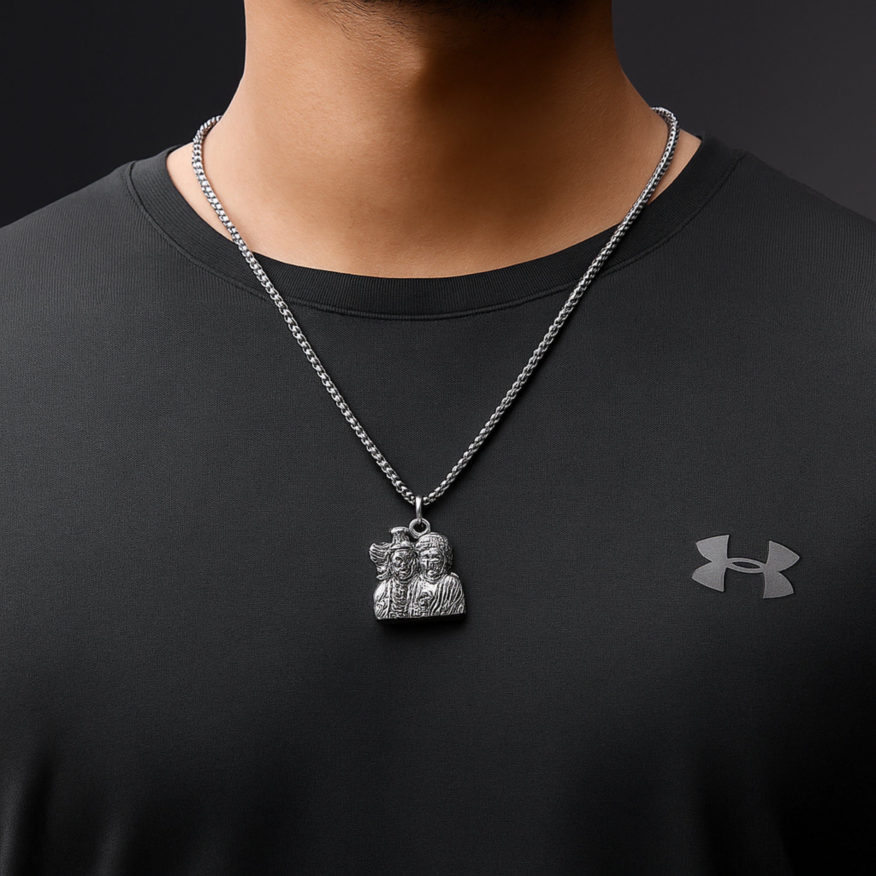 Person wearing a black shirt with an Under Armour logo and a silver necklace with a pendant. ShivaParvati LocketwithChain