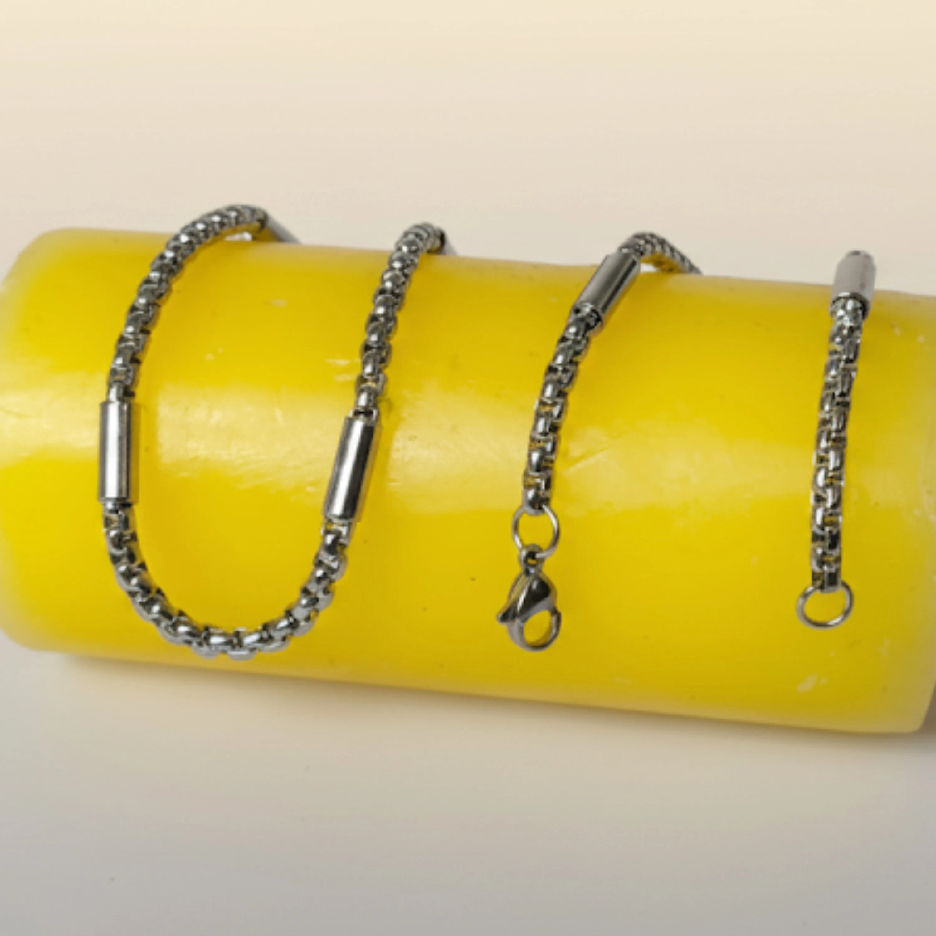 Two silver chains on a yellow cylindrical object with a white background First Dot Silver Ball Beaded Chain for Men