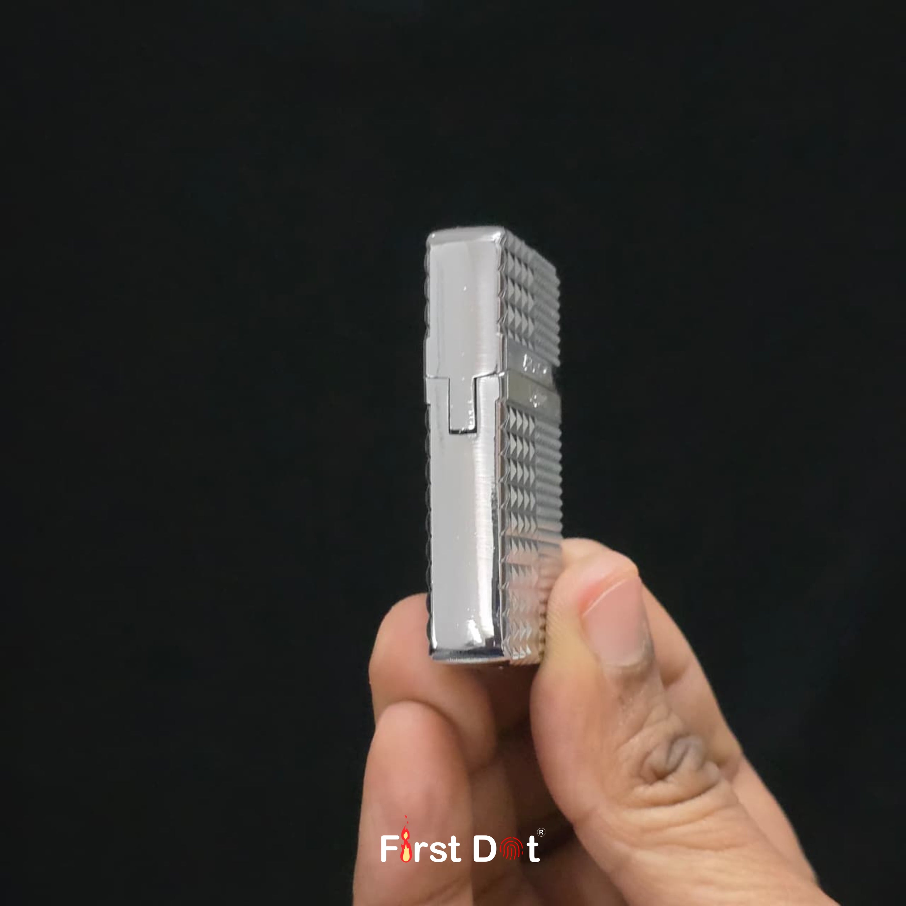 Hand holding a silver Diamond cut lighter against a black background with 'First Dot' branding.