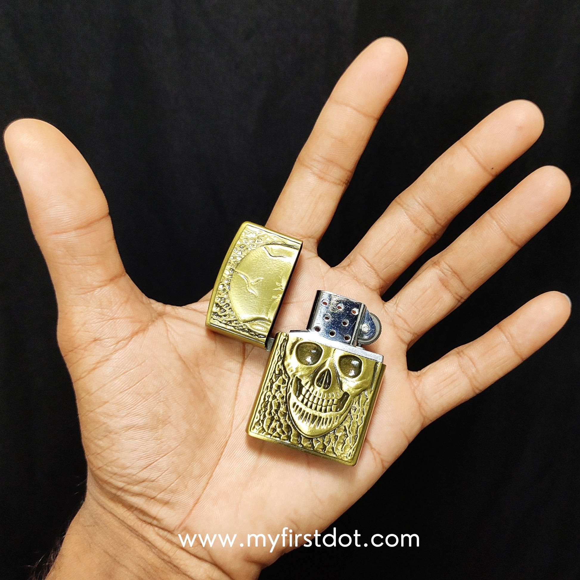 Gold skull design lighter held in a hand against a black background