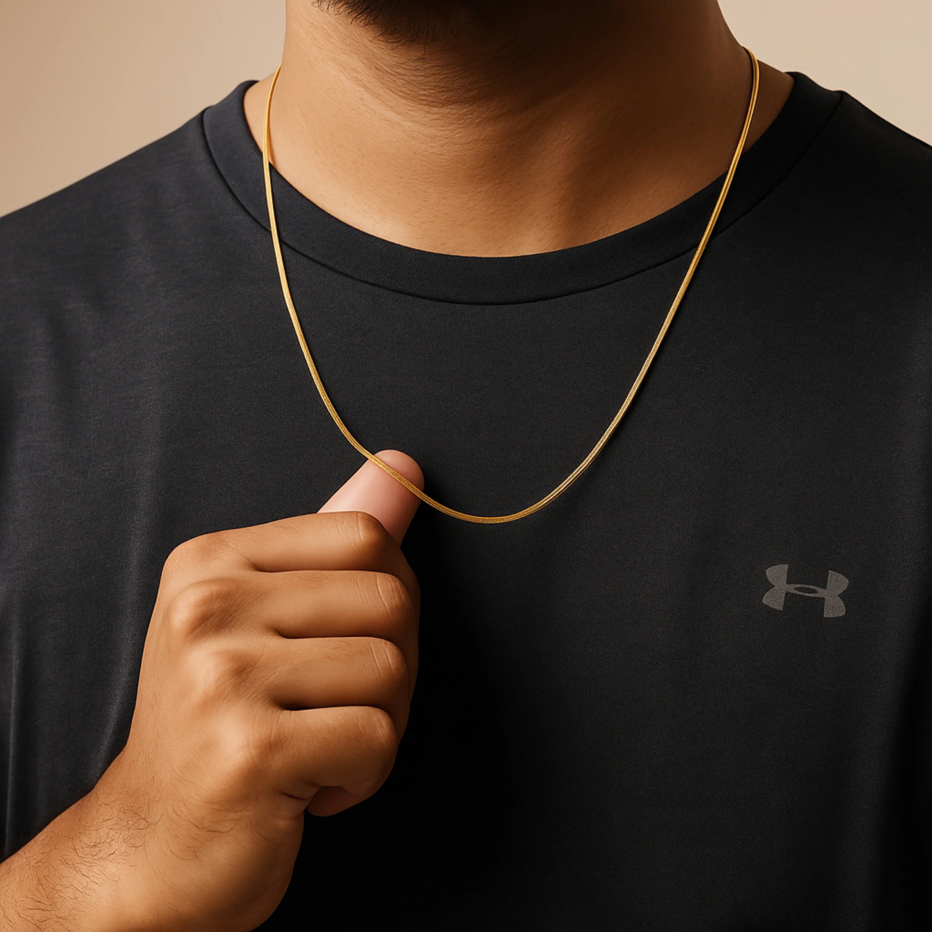 Person wearing a black shirt with a brand logo, holding a gold chain. nakeChainNecklace